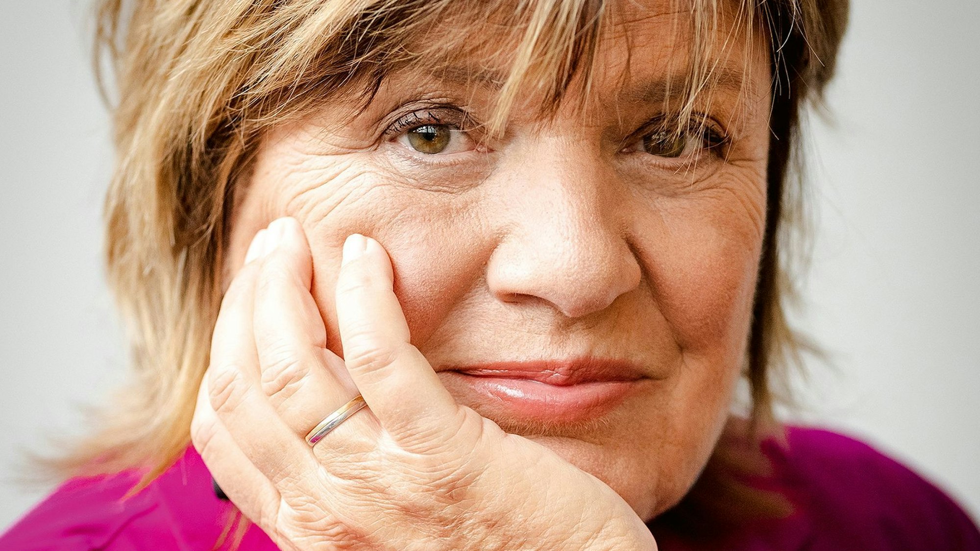 Nahaufnahme von Christine Westermann. Sie lächelt in die Kamera und stützt ihren Kopf auf ihre Hand.
