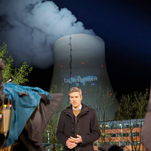 „Tagesthemen“-Moderator Ingo Zamperoni steht auf einem Balkon vor dem Kühlturm des AKW Isar 2.