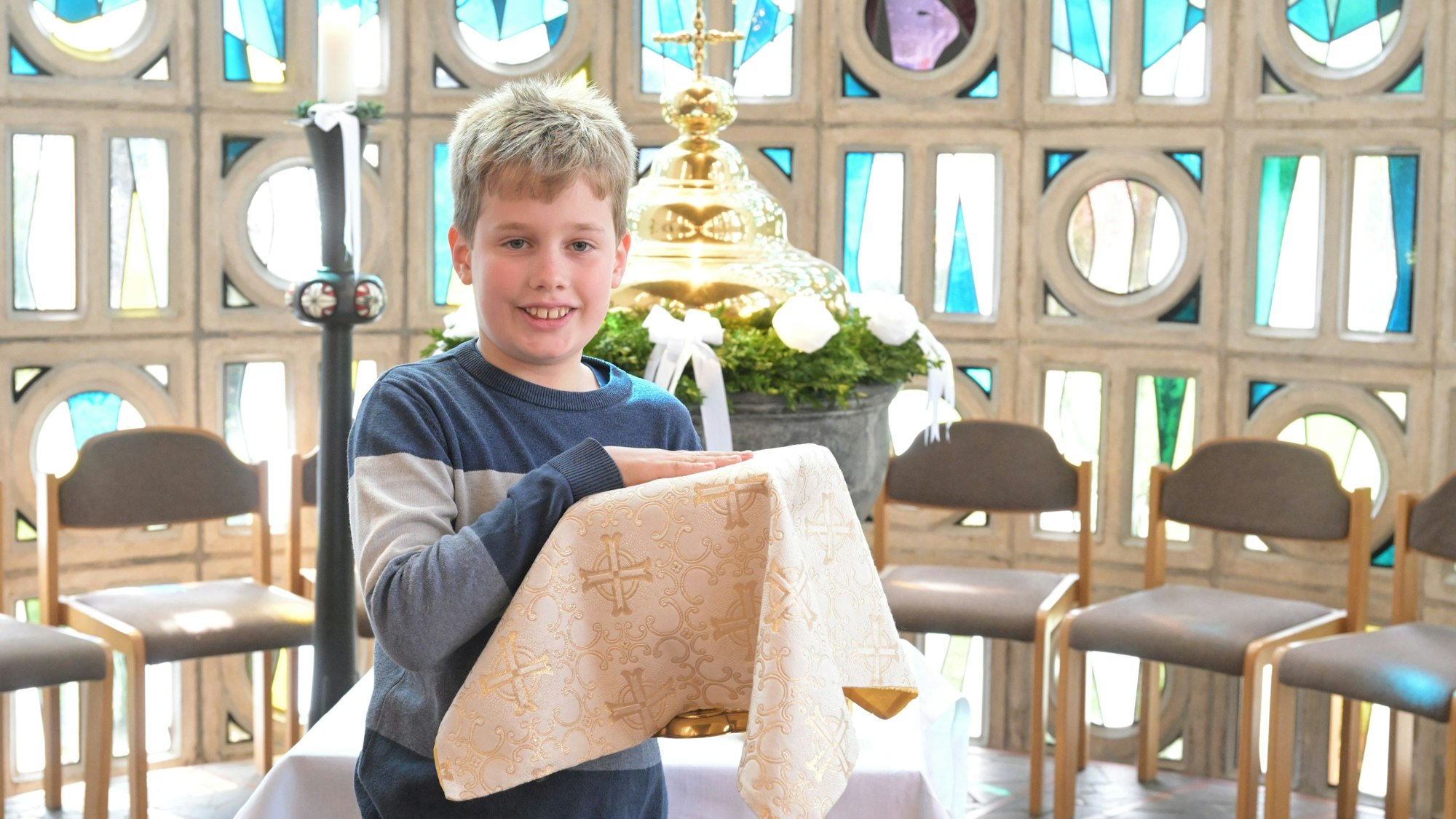 Clemens Mitschke trägt den Kelch bei der Probe zur Erstkommunionfeier.