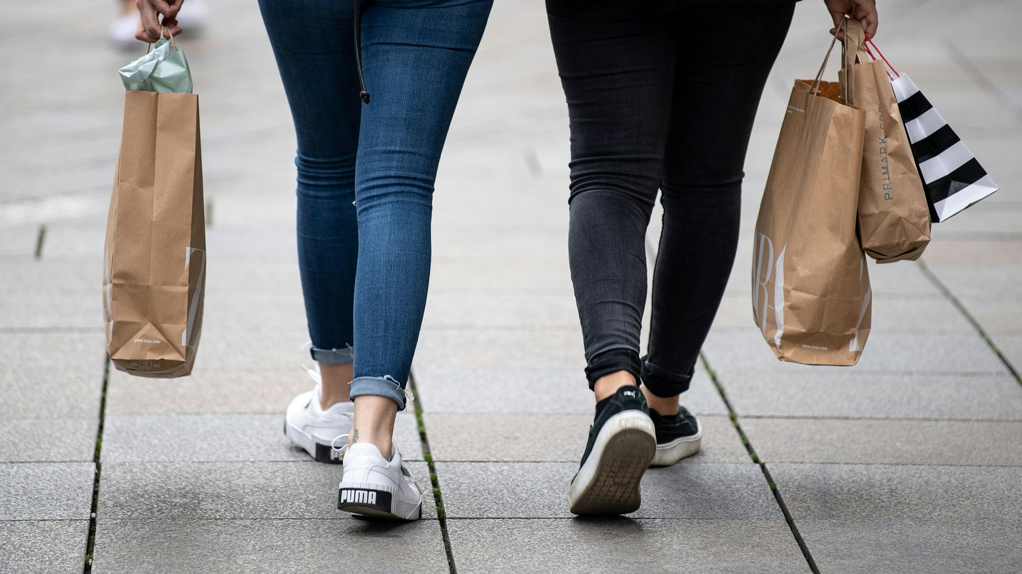 Zwei Frauen gehen mit Einkaufstüten durch die Stuttgarter Innenstadt.