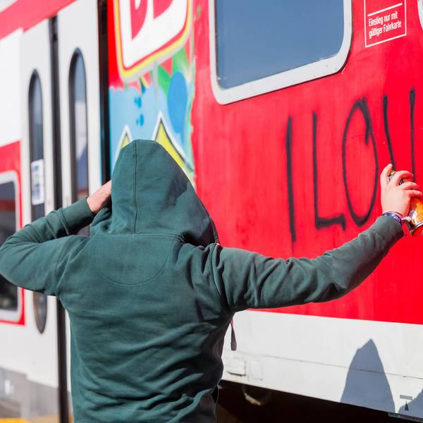 Ein Sprayer besprüht illegal einen Zug.