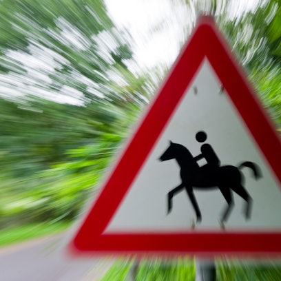 Ein Achtung Reiter-Schild an einer Straße.