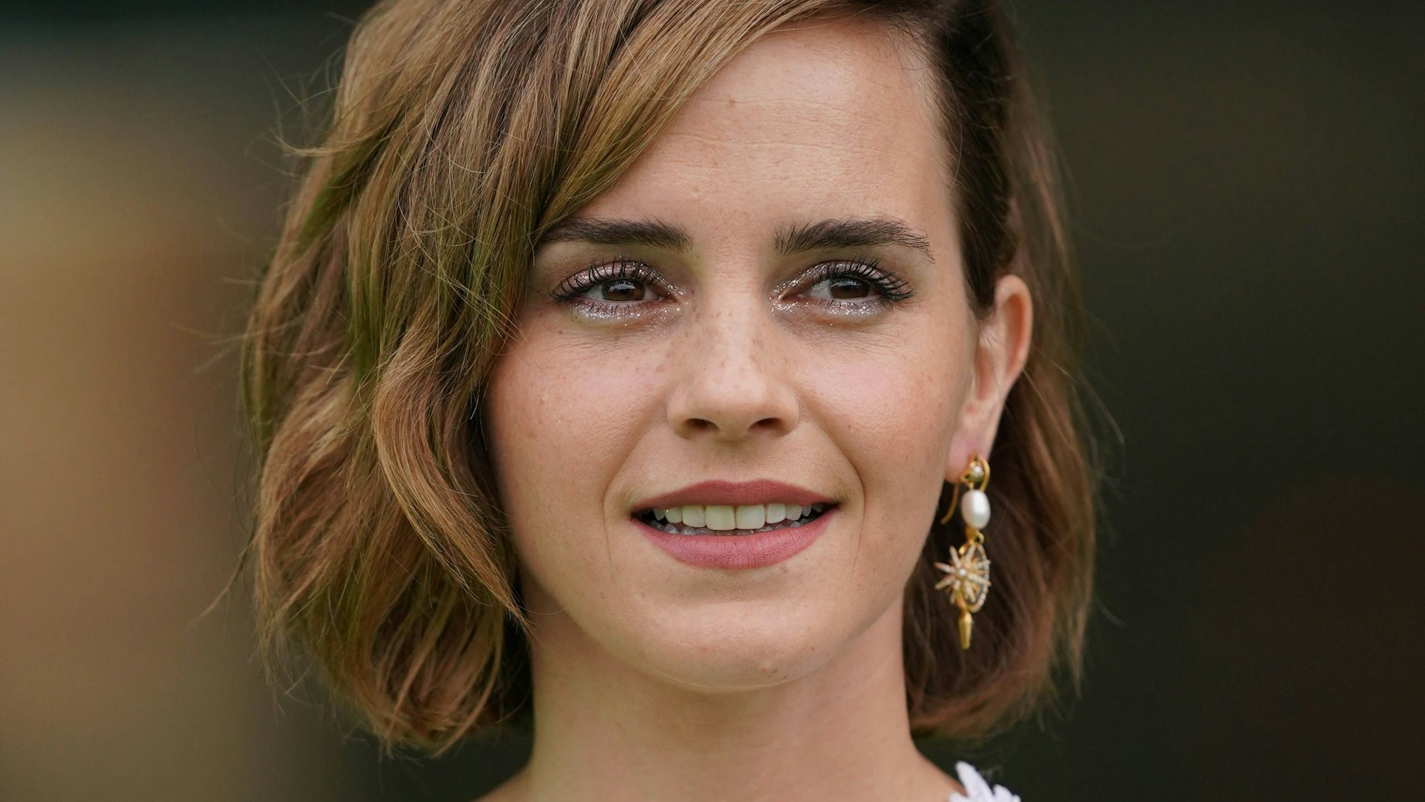 Emma Watson im Jahr 2018. Sie lächelt leicht und trägt die Haare seitlich, sodass ein großer Ohrring zu sehen ist.