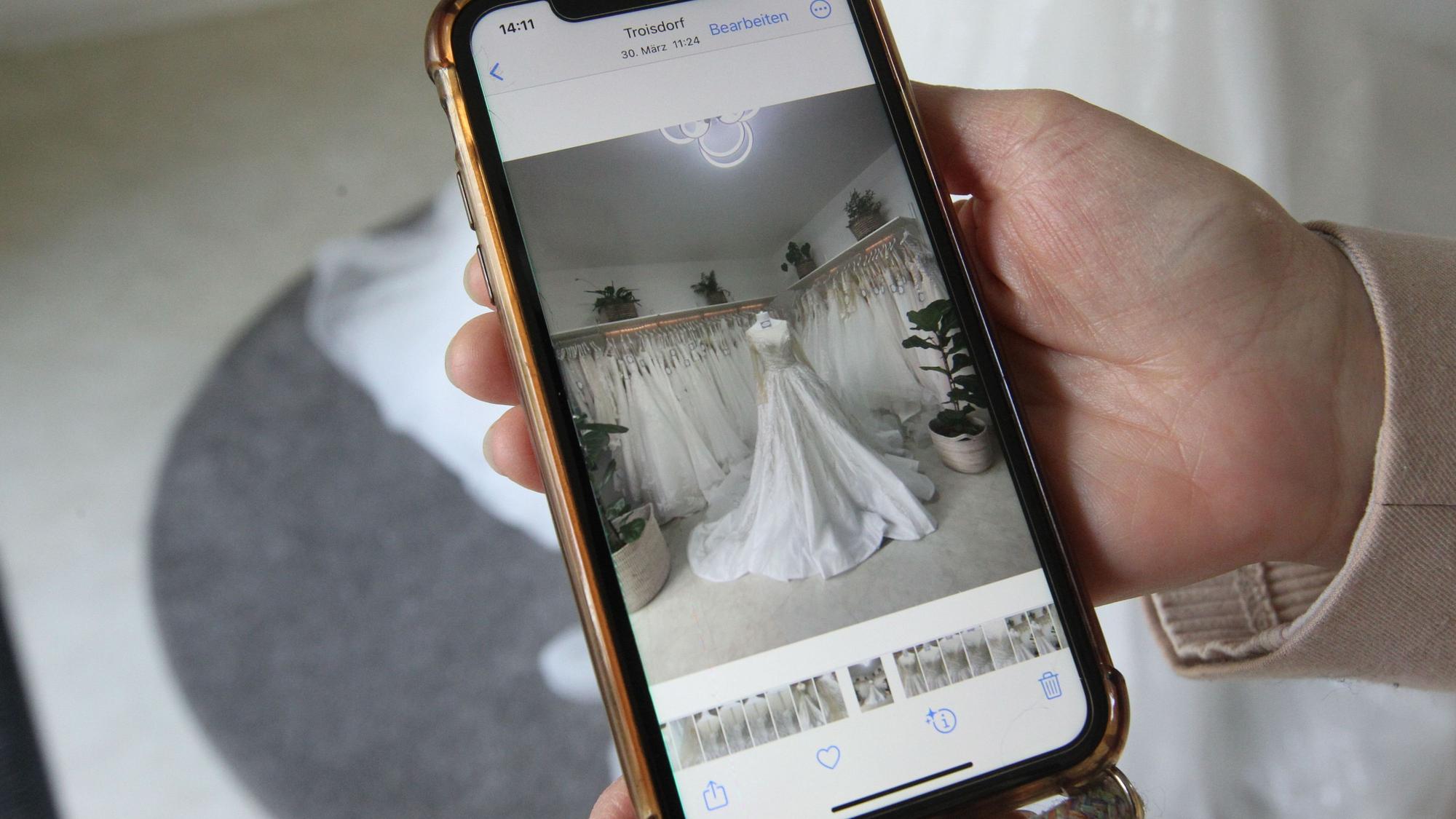 Auf einem Smartphone ist ein Bild von einem Brautkleid zu sehen.