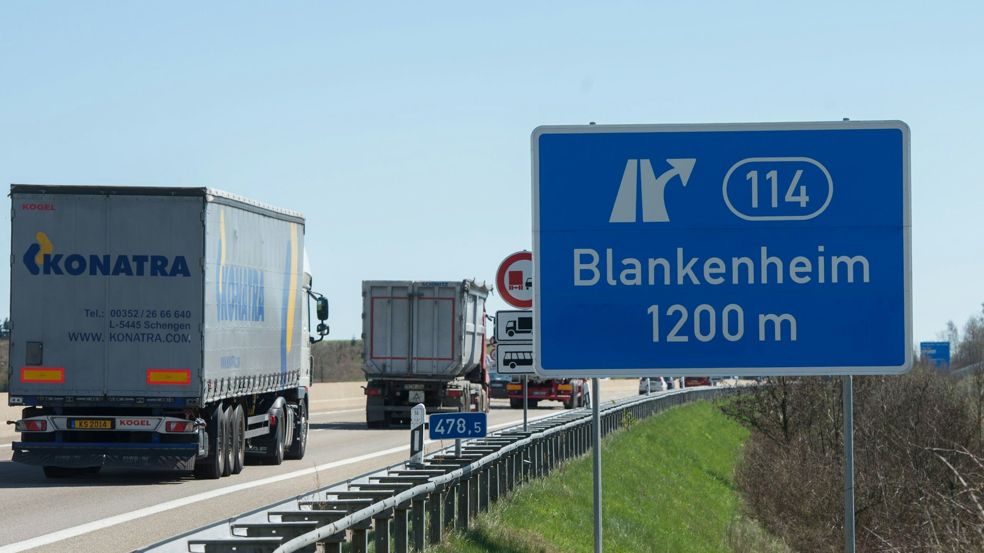 Auf der Autobahn 1 zeigt ein blaues Schild die Ausfahrt Blankenheim in 1200 Metern an. Links fahren Lkw daran vorbei.