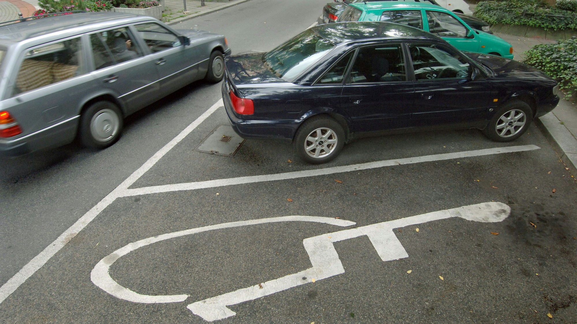 Ein Pkw fährt an einem Behindertenparkplatz vorbei.