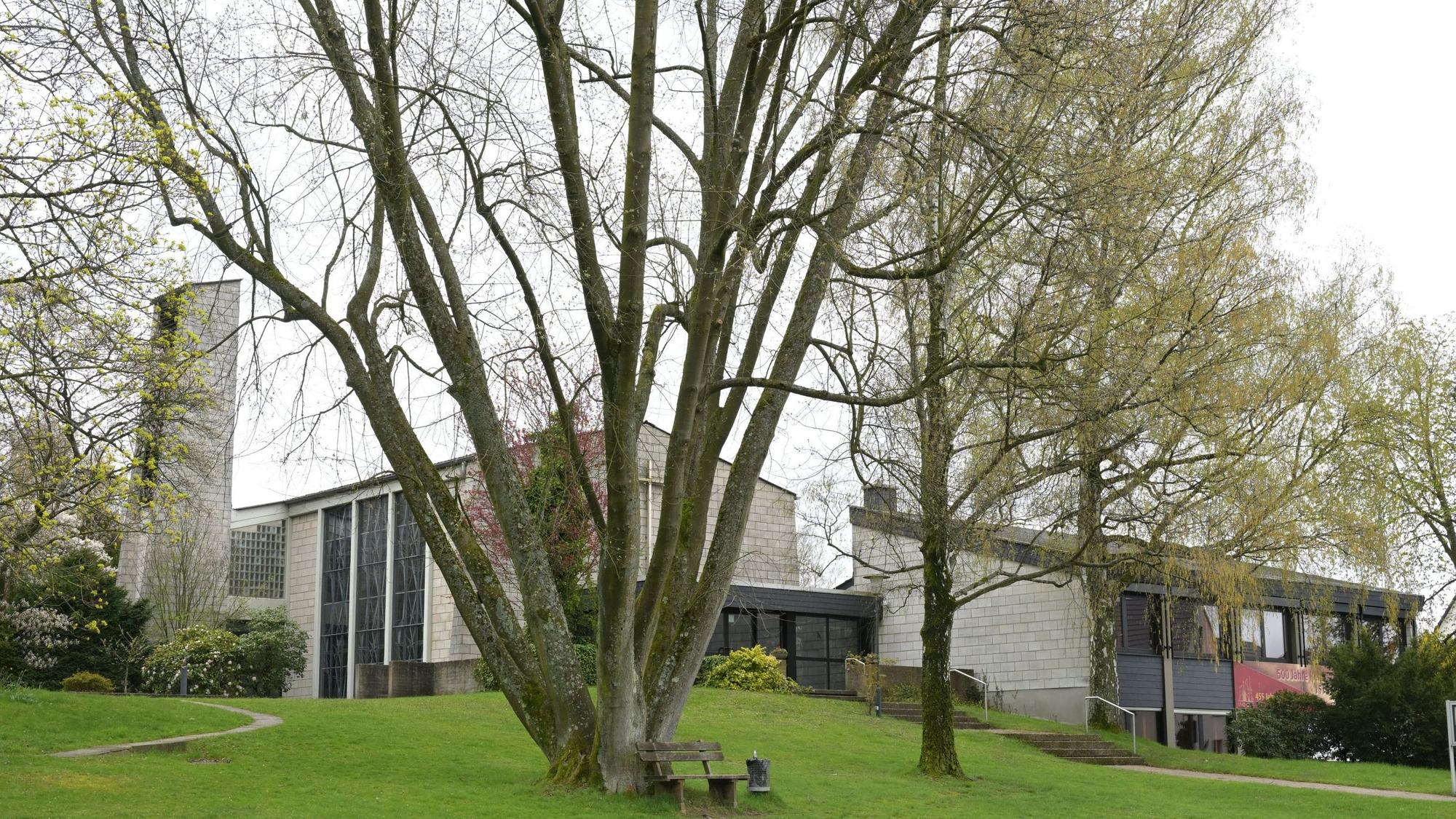 ein weißer moderner Kirchenbau und ein weißes Gemeindehaus, im Vordergrund eine Wiese