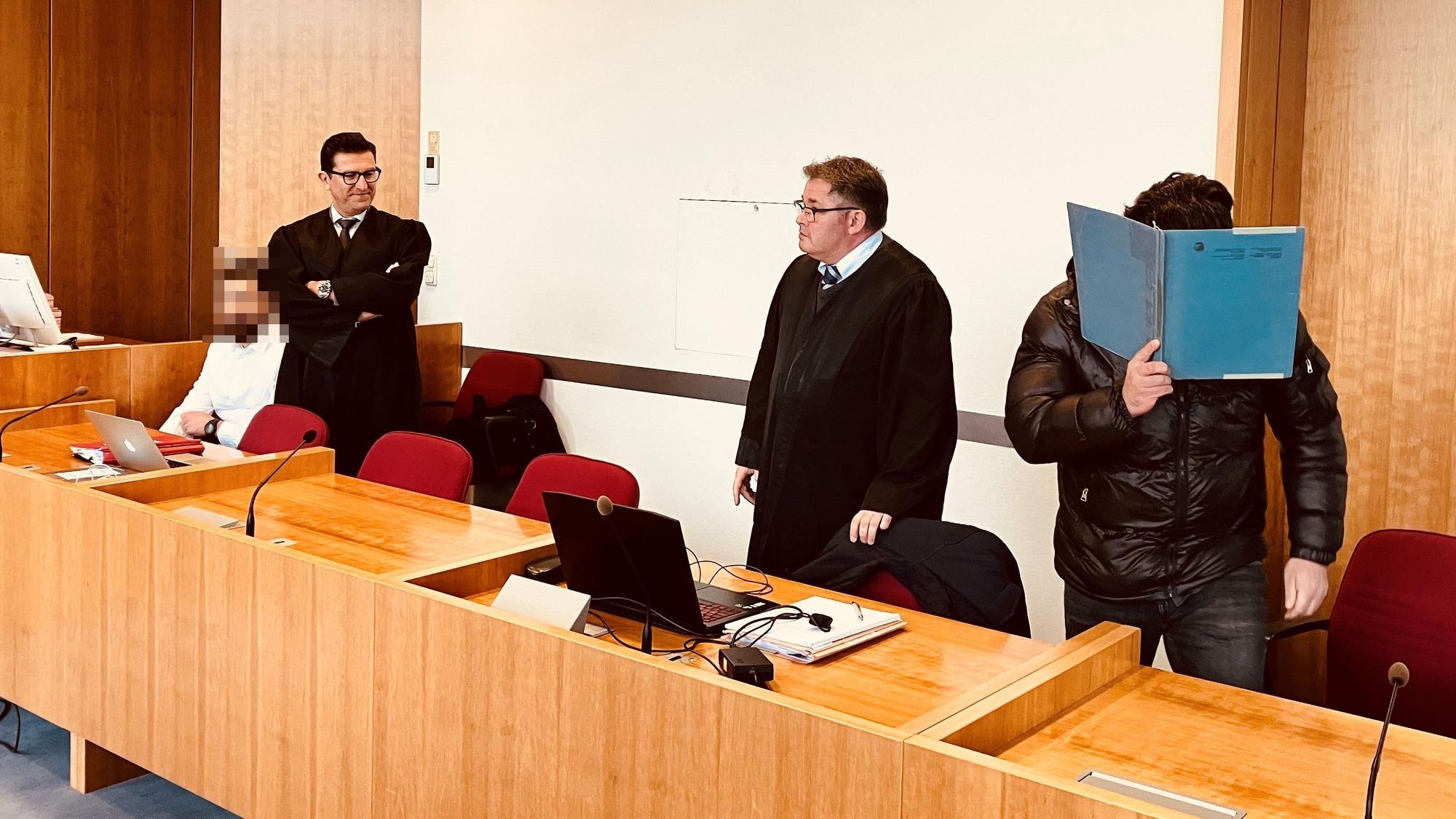 Angeklagte und Verteidiger sitzen und stehen im Gericht.