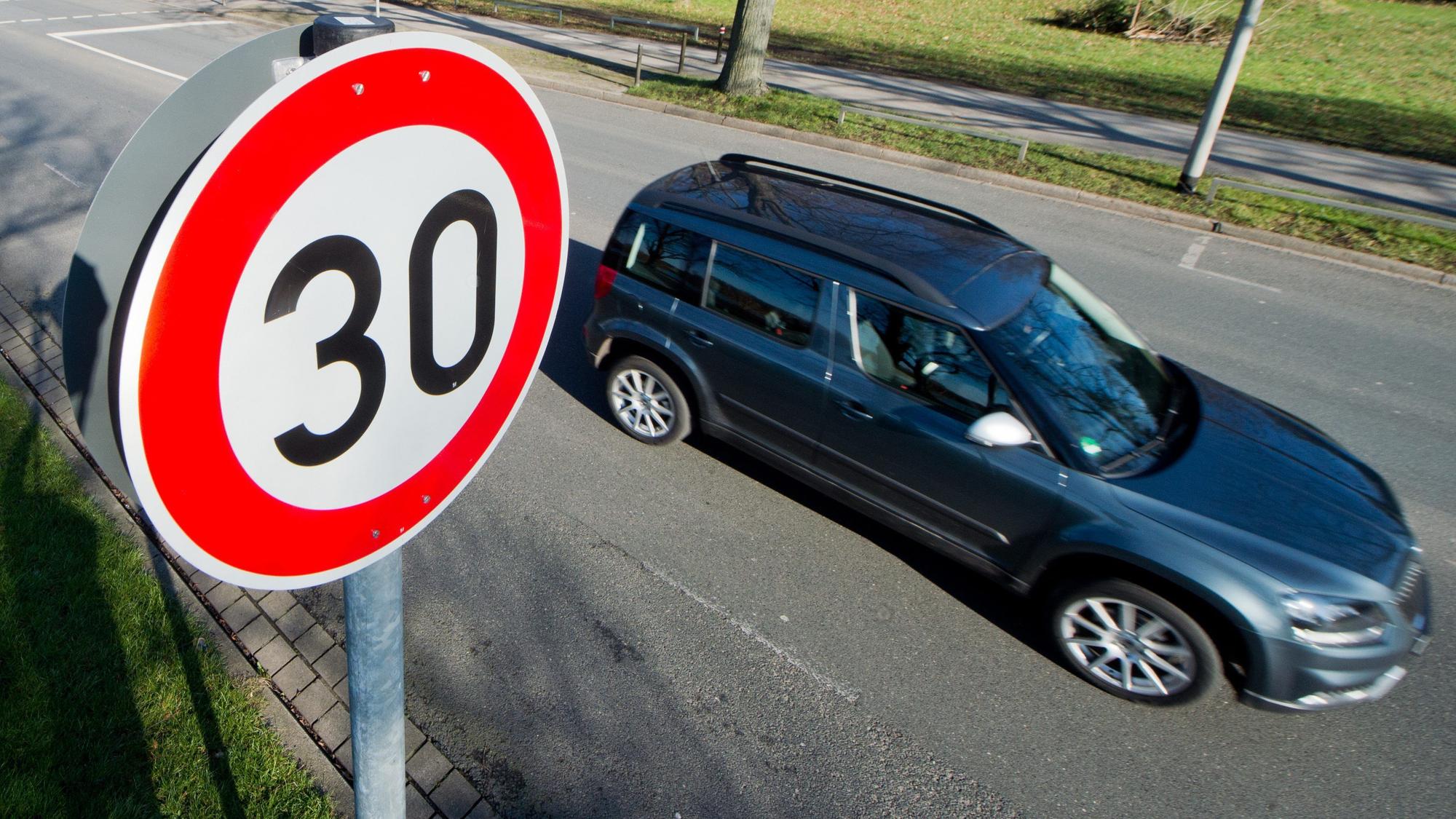 Ein Auto fährt an einem Verkehrsschild für eine Geschwindigkeitsbegrenzung von 30 Stundenkilometer vorbei.