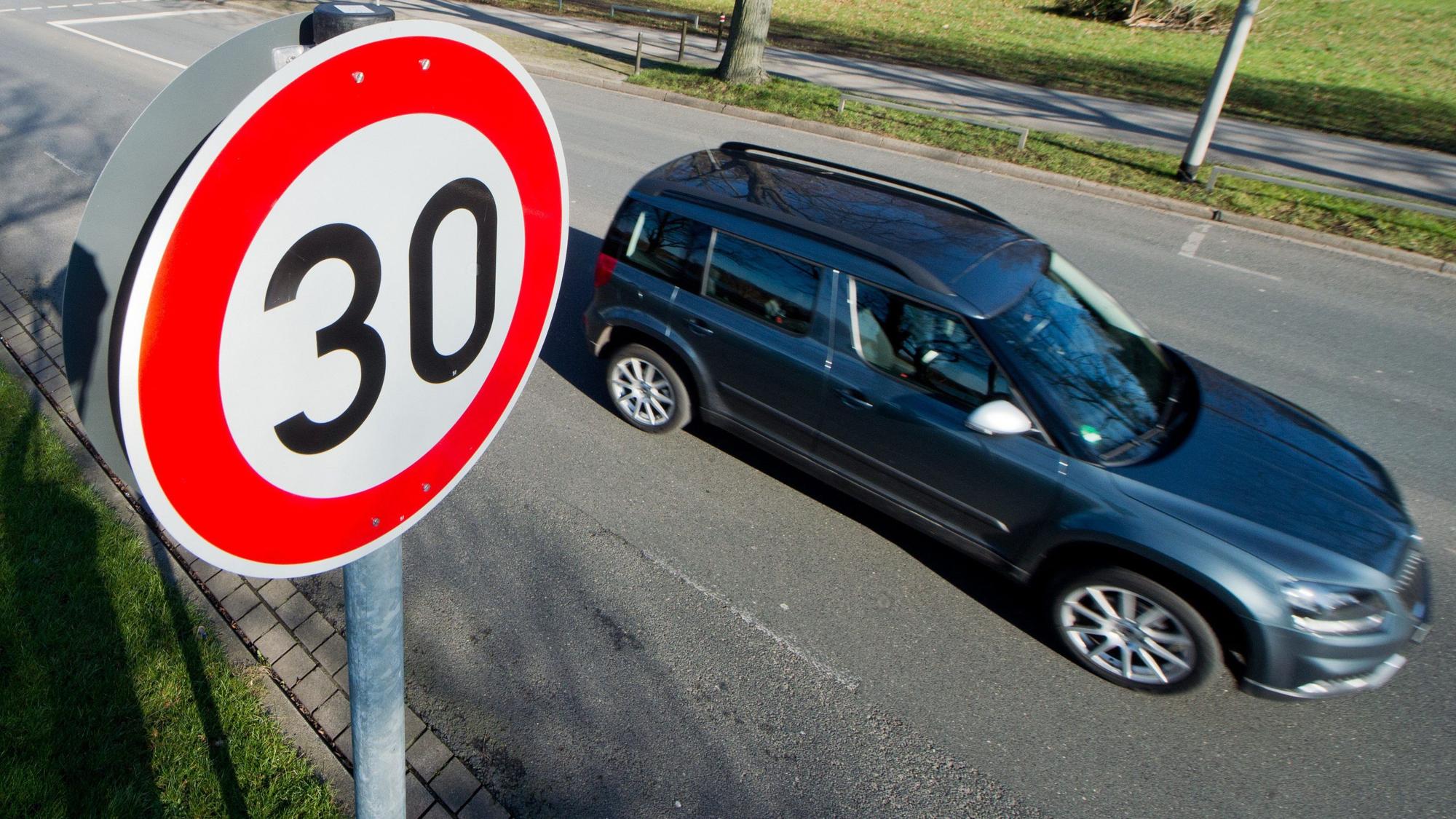 Ein Auto fährt an einem Verkehrsschild für eine Geschwindigkeitsbegrenzung von 30 Stundenkilometer vorbei.