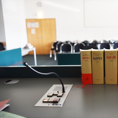 Gesetzesbücher stehen auf dem Tisch in einem Gerichtssaal.