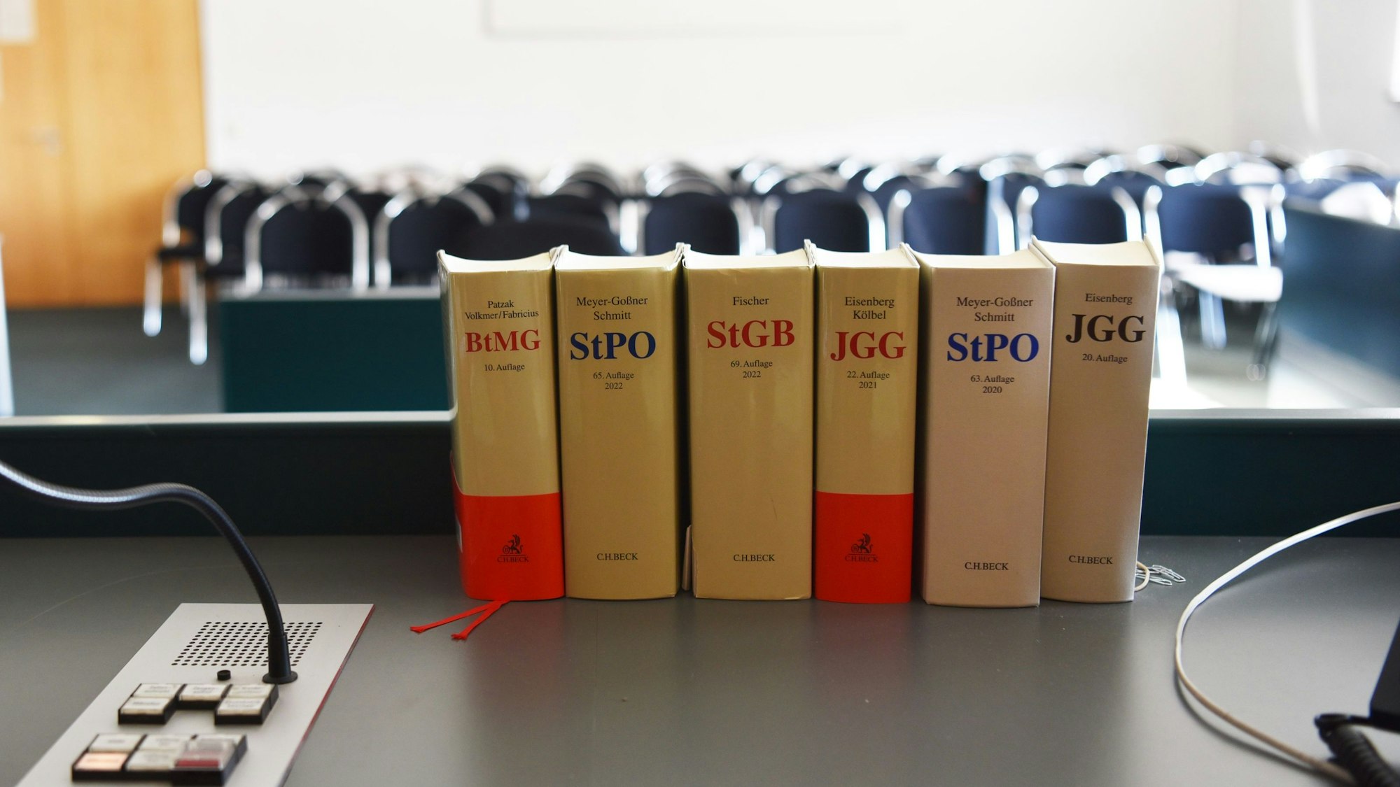 In einem Gerichtssaal stehen verschiedene Gesetzessammlungen auf dem Richtertisch.