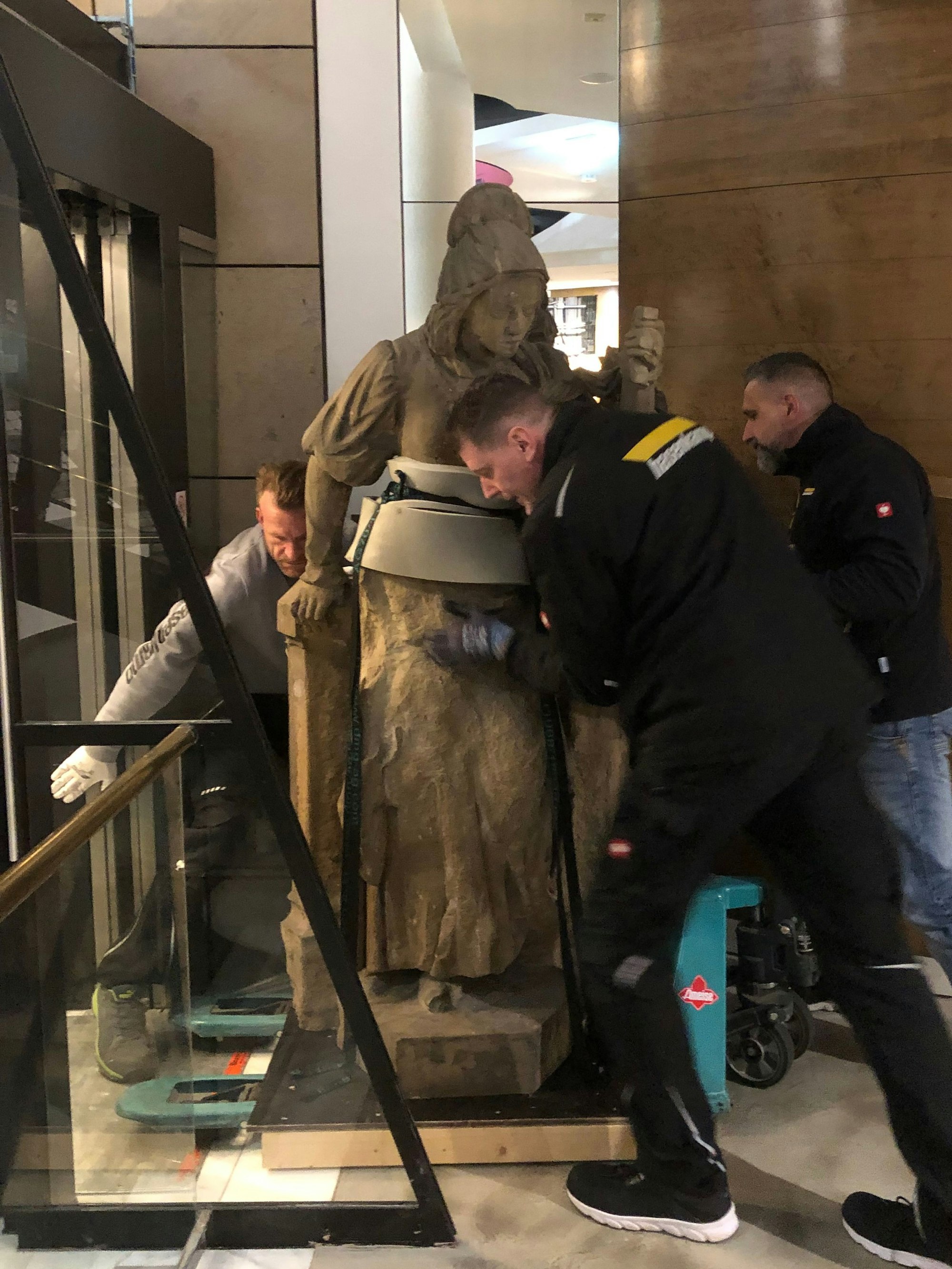 Arbeiter bugsieren die „Schneidersfrau“ aus dem Aufzug.