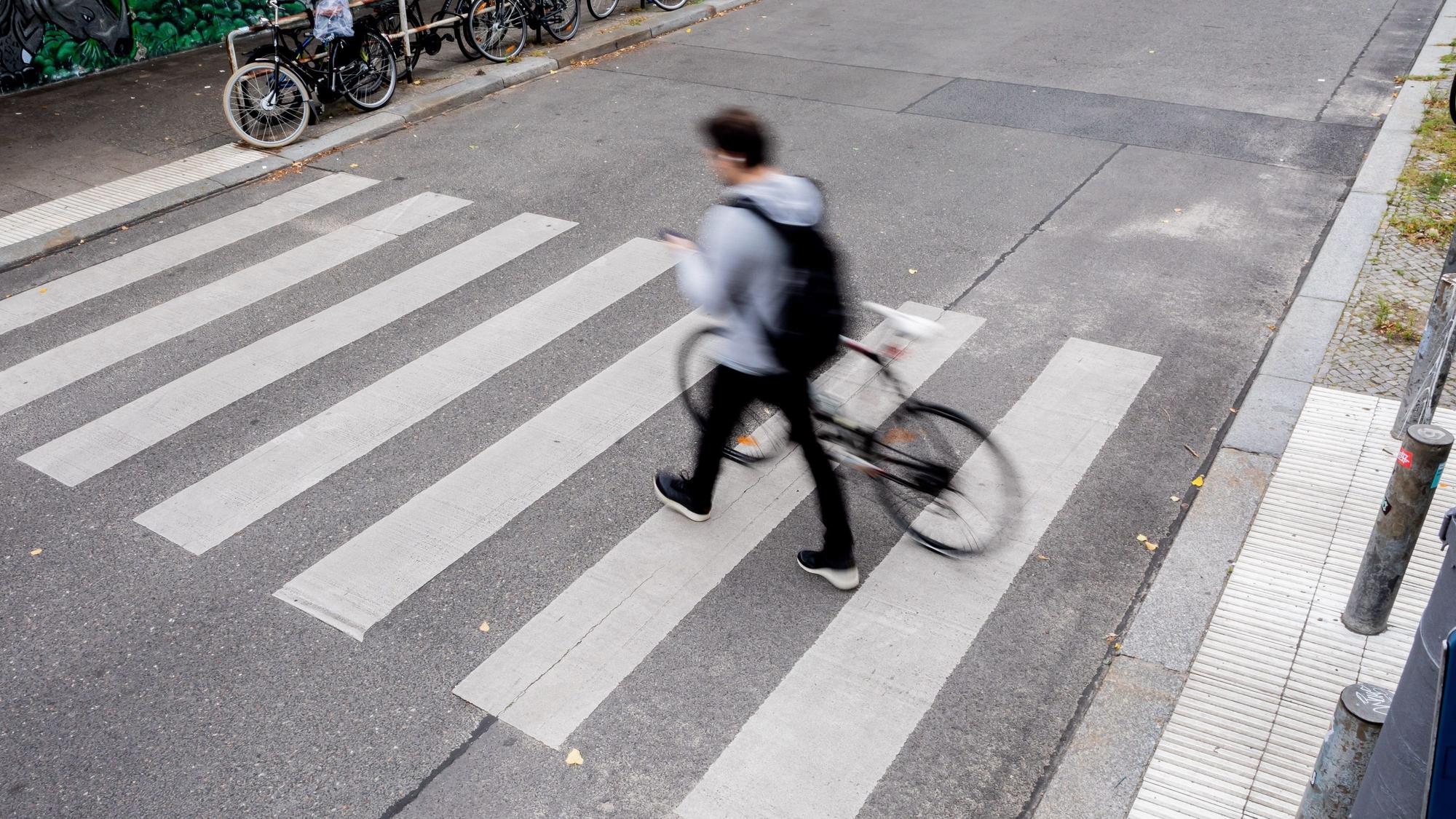 Ein Mann schiebt sein Fahrrad über einen Zebrastreifen. (Symbolbild)