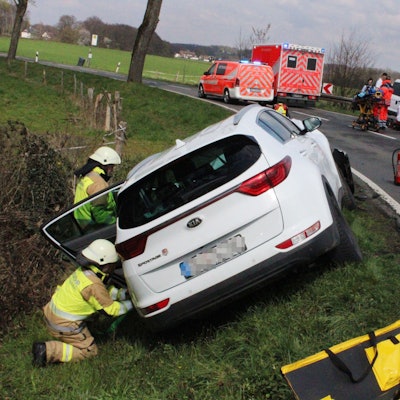 Schwer beschädigte Autos stehen neben einer Straße. Feuerwehrleute und Rettungsdienstmitarbeitende sind im Einsatz.