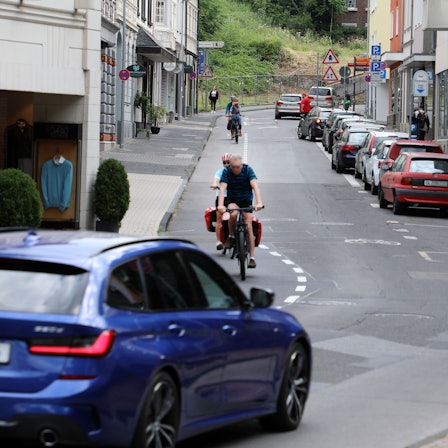 Die Laurentiusstraße in Bergisch Gladbach mit Fahrradfahrenden, Autos und Häusern.