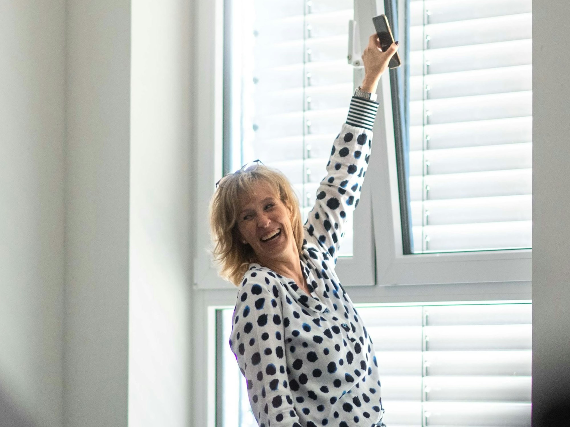 Die Gesamtschullehrerin hält ihr Handy ans gekippte Fenster, um dort eine Netzanbindung zu finden.