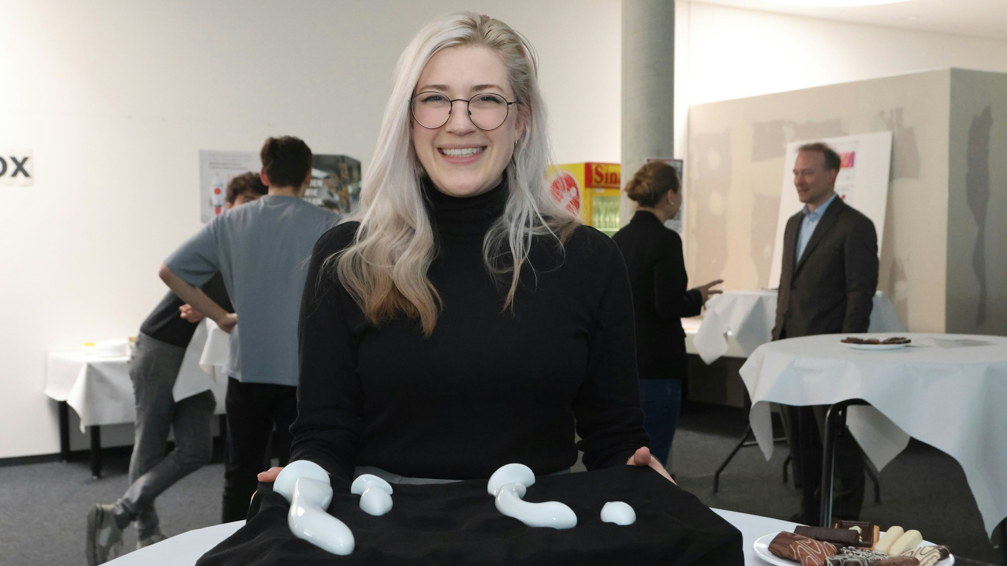 Eine junge Frau hält eine Palette mit Sexspielzeug aus Porzellan in den Händen.