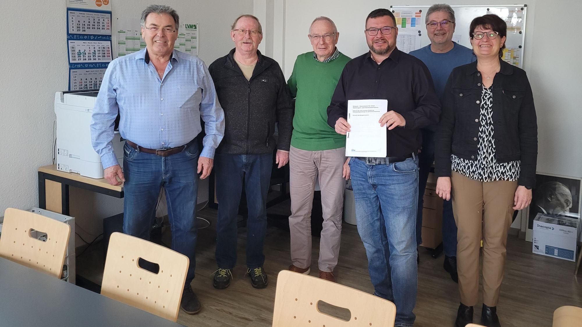 Mehrere Personen stehen zusammen, eine hält ein Papier in der Hand.