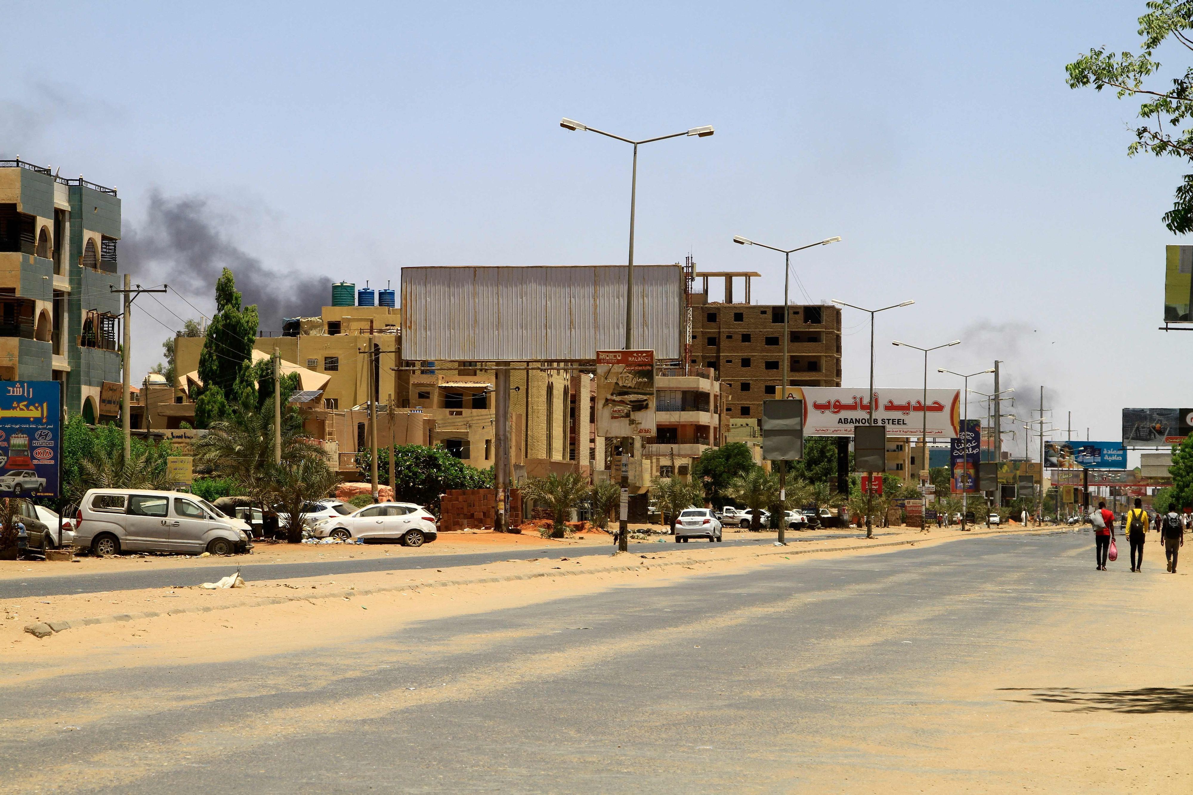 Straße im Sudan, am Himmel ist Rauch zu sehen.