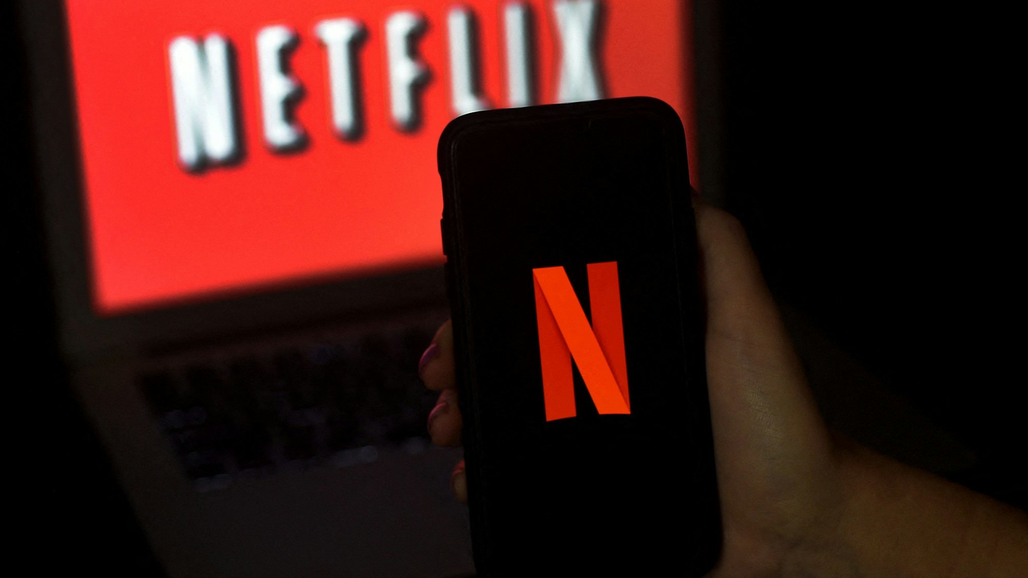 Das Logo des Streamingdienstes Netflix ist auf einem Smartphone und auf einem Laptop zu sehen. Netflix hat angekündigt, stärker gegen das Teilen von Login-Daten vorgehen zu wollen. (Symbolbild)
