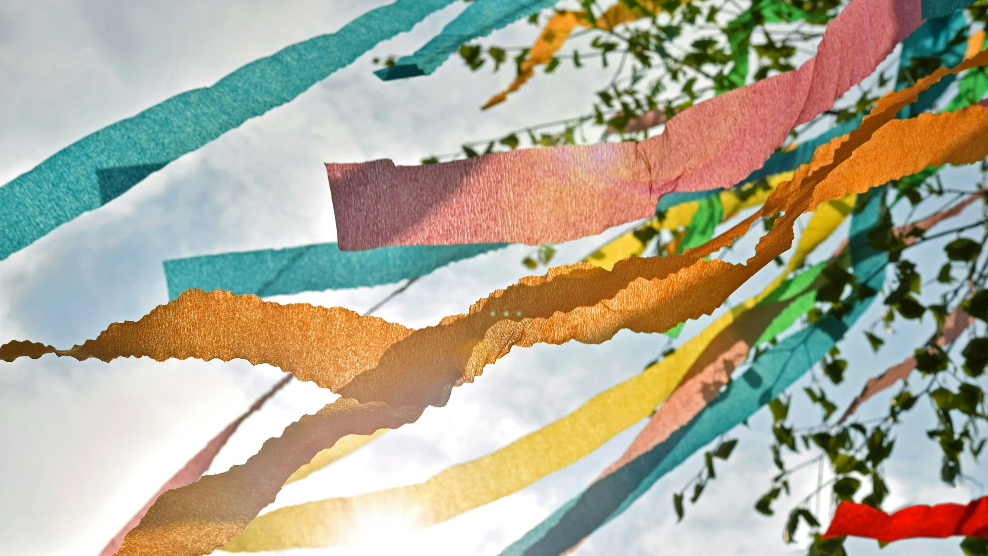 Bunte Bänder an einem Maibaum flattern im Wind.