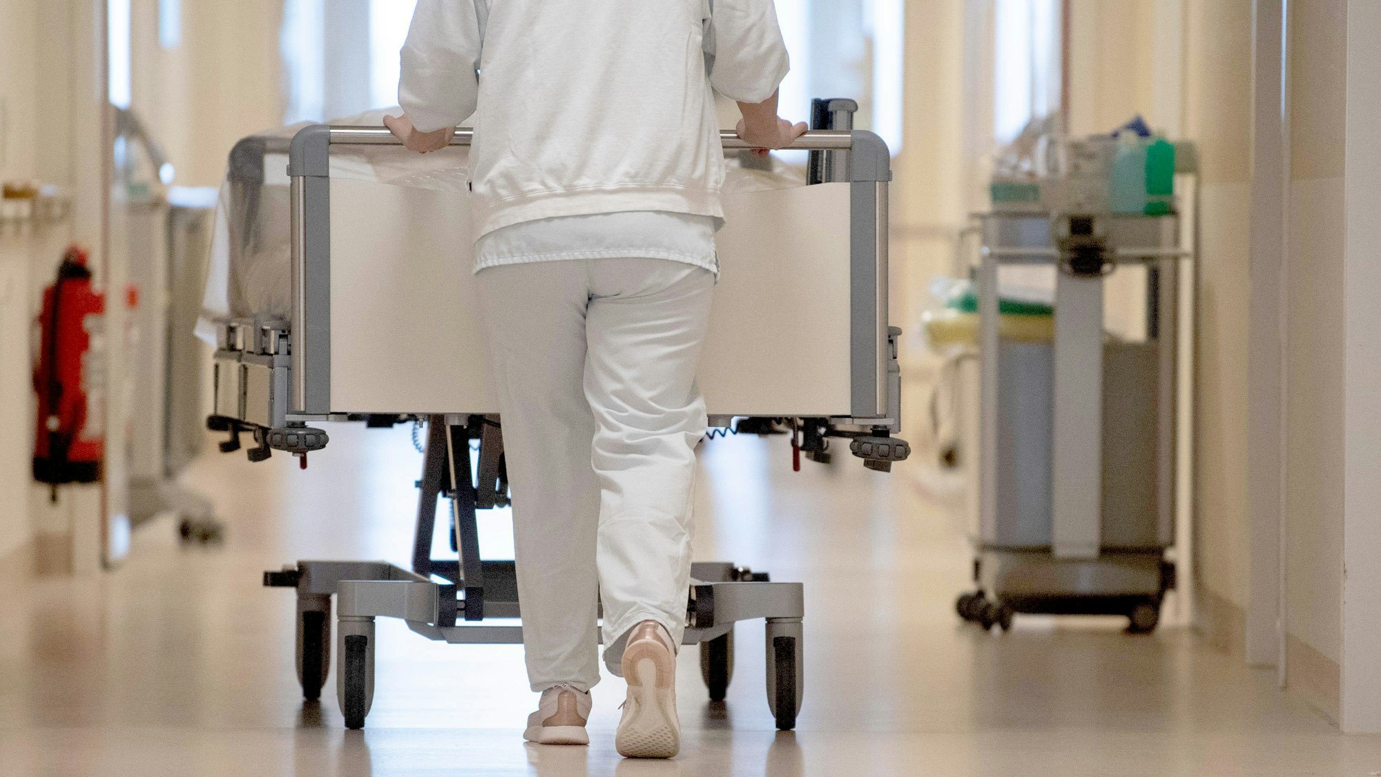 Eine Krankenpflegerin schiebt ein Krankenbett durch einen Krankenhausflur. (Archivbild)