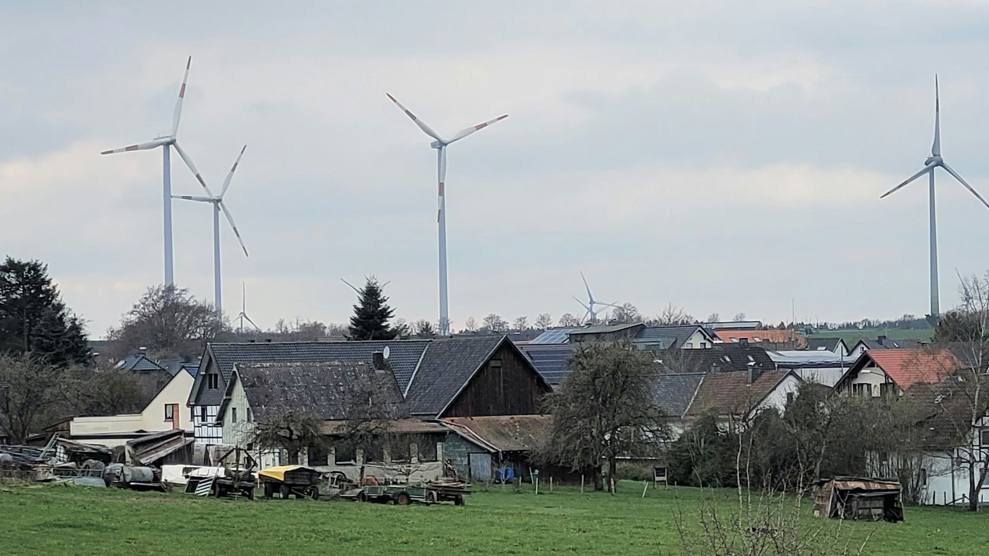 Im Vordergrund ein Dorf, dahinter stehen Windräder.