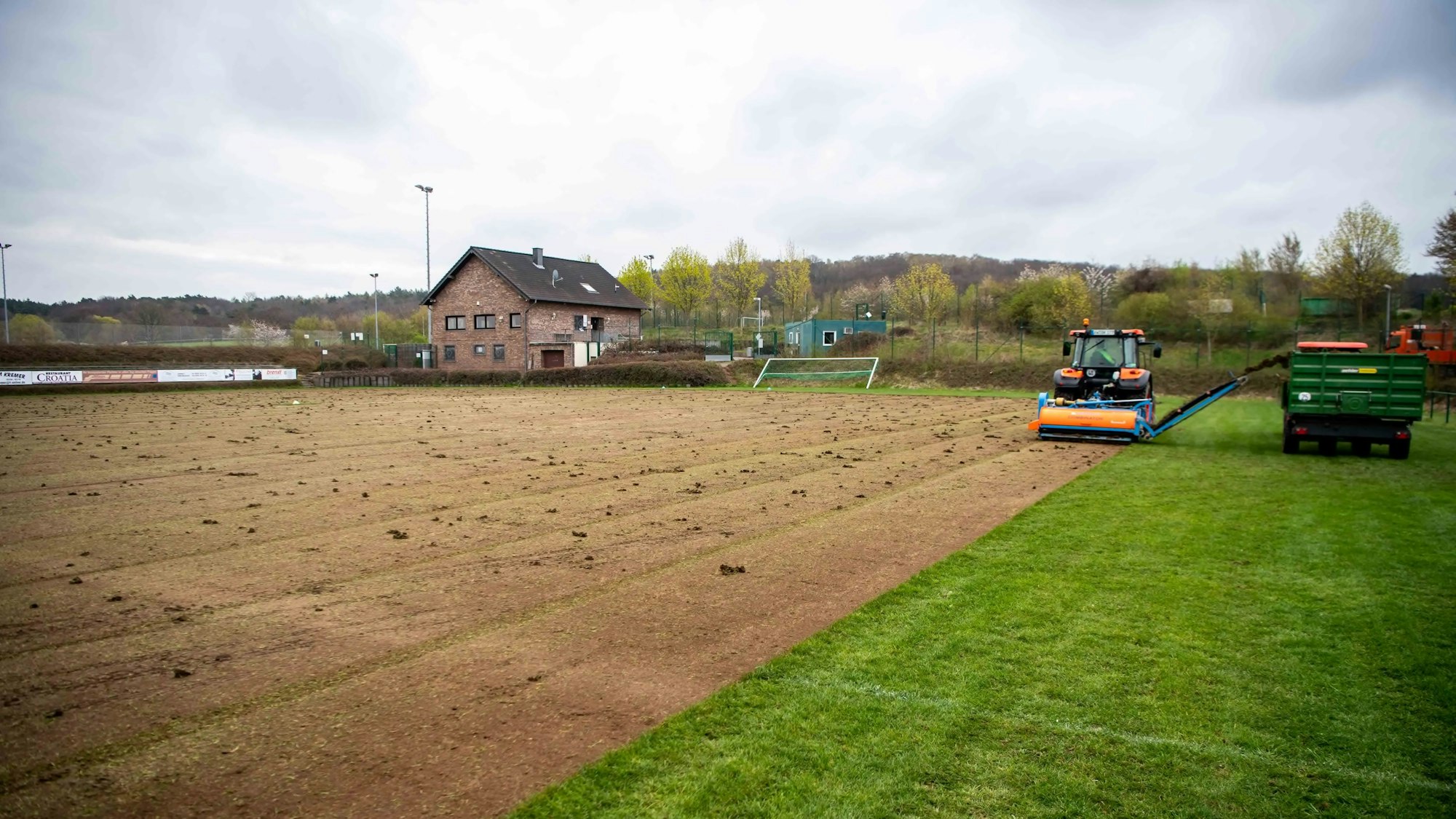 Der Rasen eines Fußballplatzes wird mit einer Maschine abgeschält.