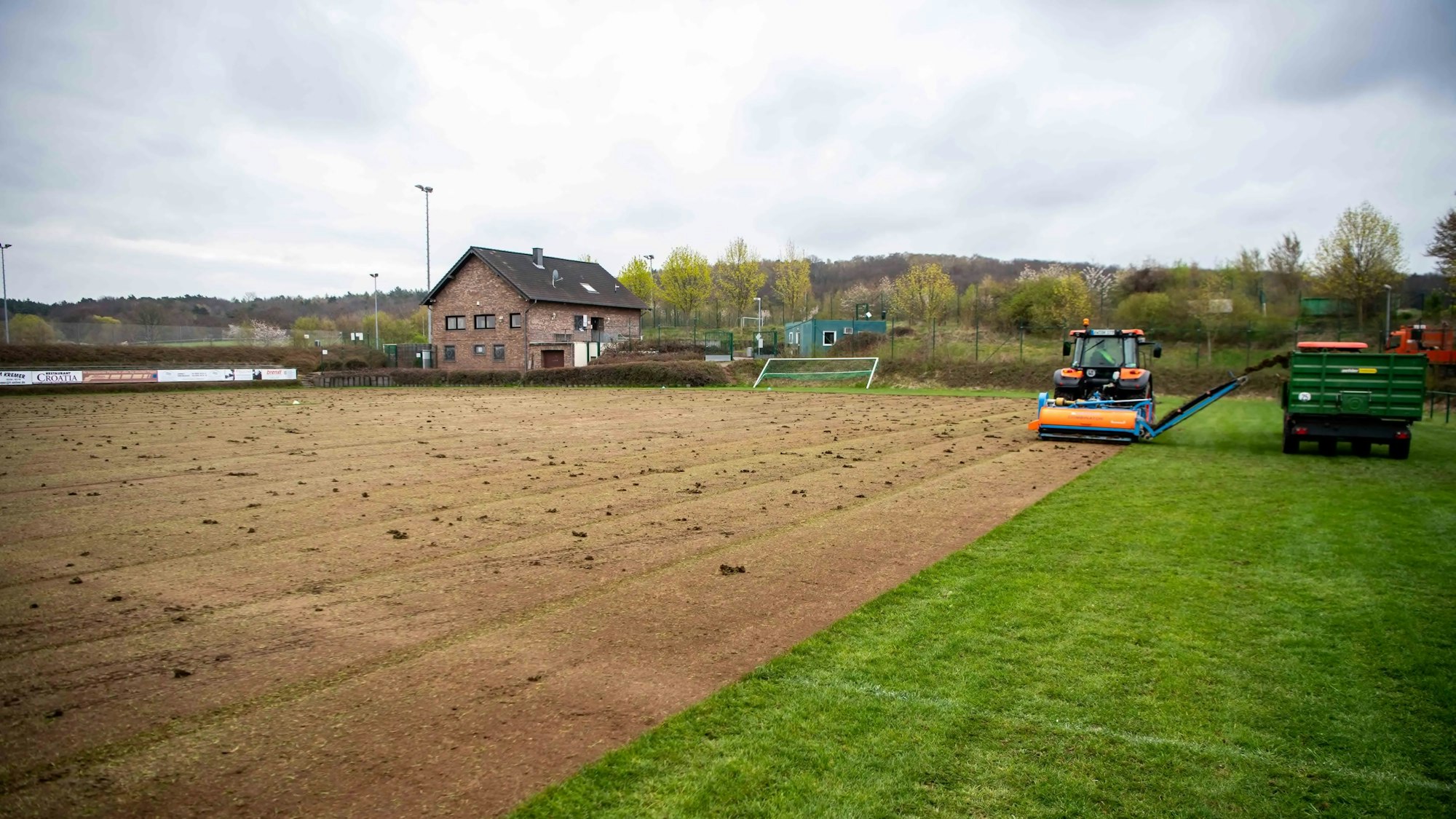 Der Rasen eines Fußballplatzes wird mit einer Maschine abgeschält.