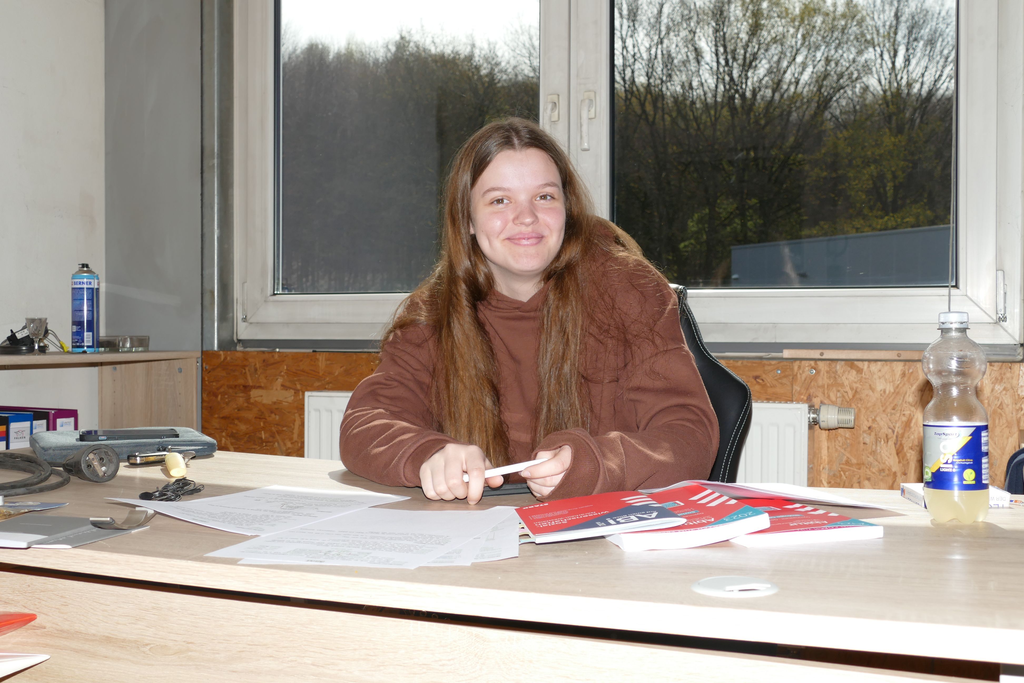 Eine junge Frau sitzt am Schreibtisch.