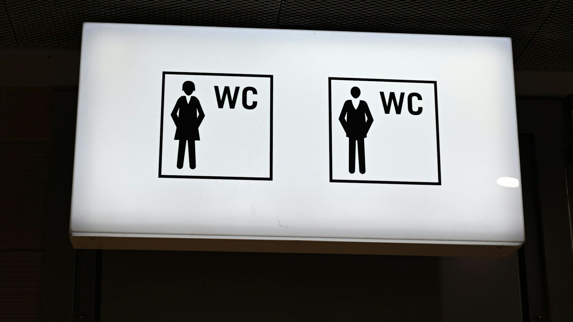 Ein beleuchtetes Hinweisschild mit Piktogrammen ist in der B-Ebene der Konstablerwache vor einem öffentlichen WC für Frauen und Männer angebracht.