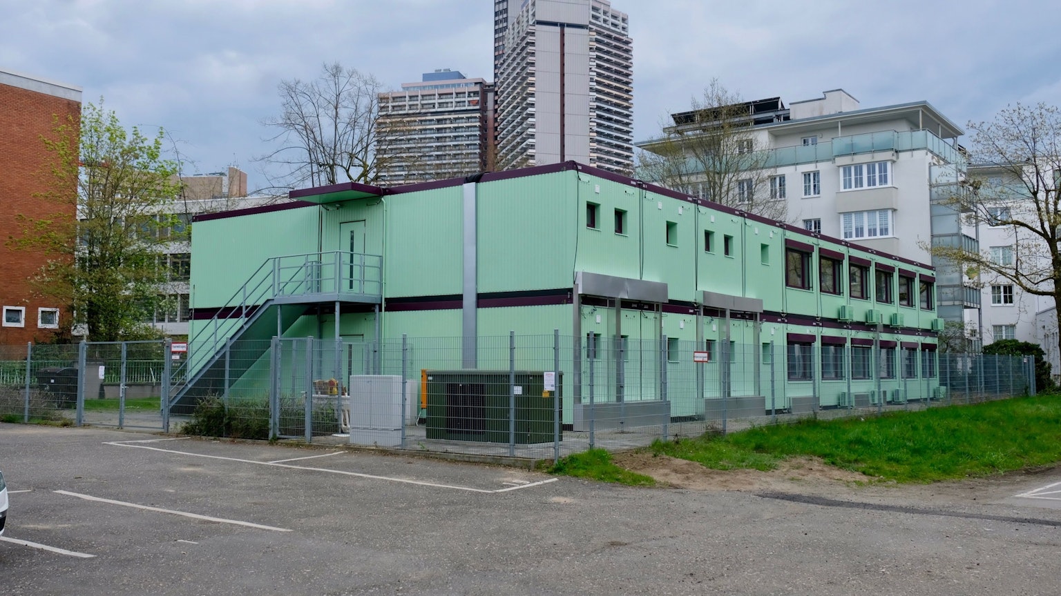 Zweistöckige Container sind zu sehen, im Hintergrund die Türme des Uni-Centers.