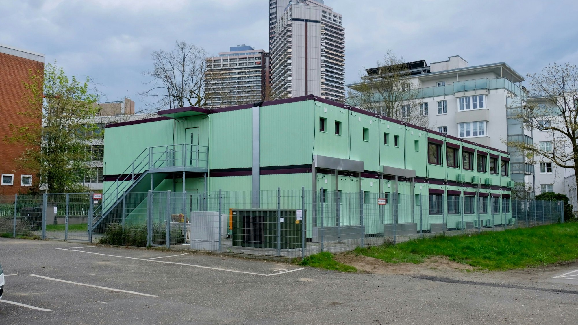 Zweistöckige Container sind zu sehen, im Hintergrund die Türme des Uni-Centers.