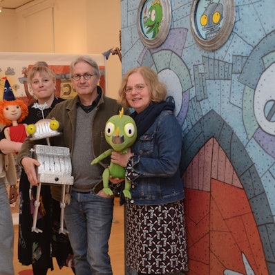 Drei Frauen und ein Mann stehen vor einem Bild, das Ritter Rost zeigt.