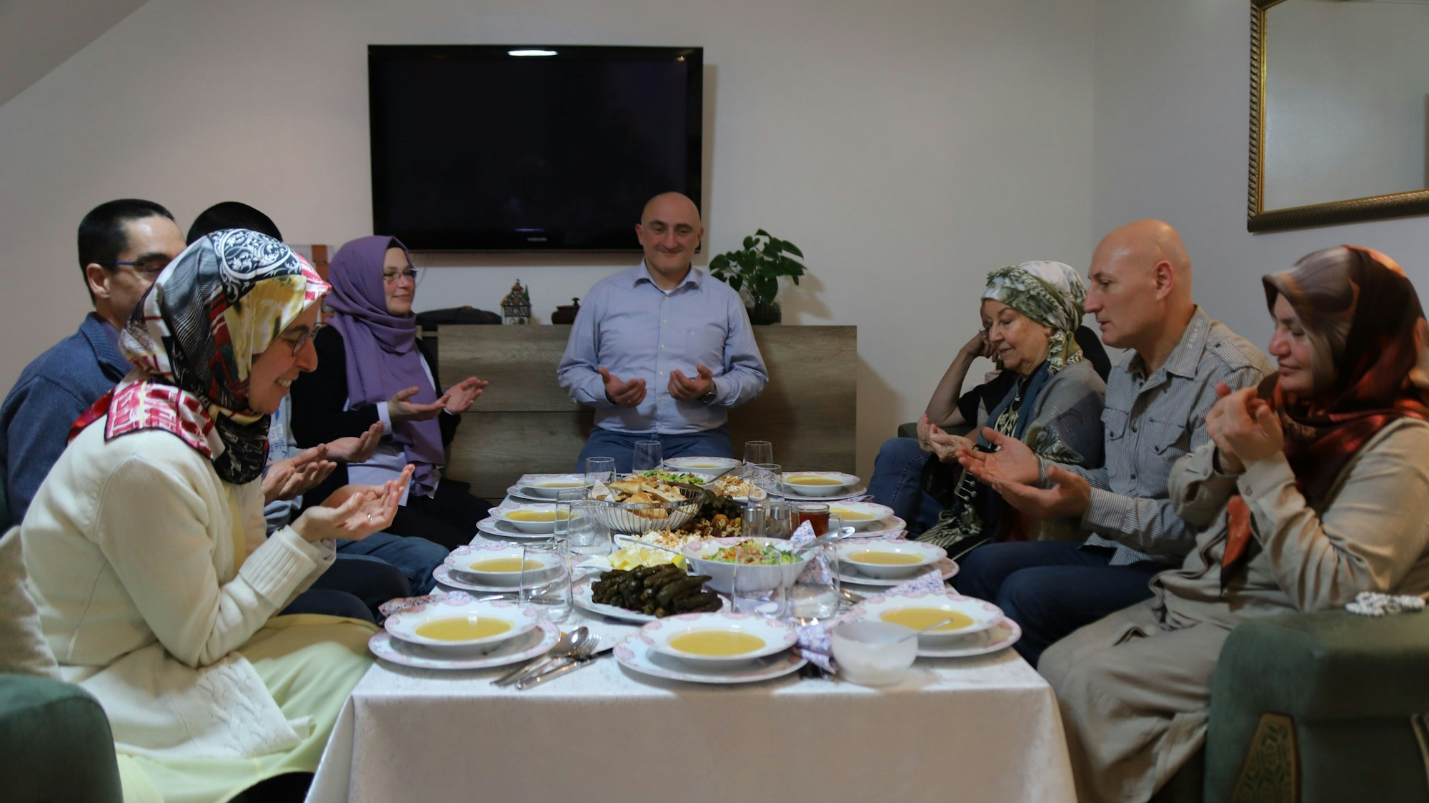 An einem reich gedeckten Tisch beten die Freunde gemeinsam vor dem Fastenbrechen.