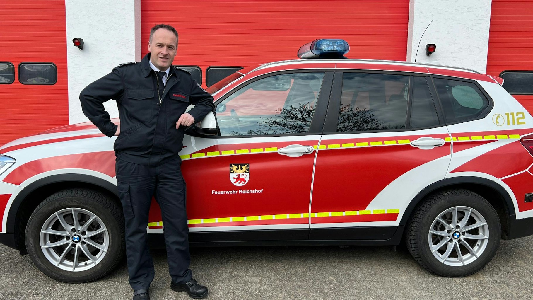 Sascha Frede posiert vor einem PKW der Feuerwehr.