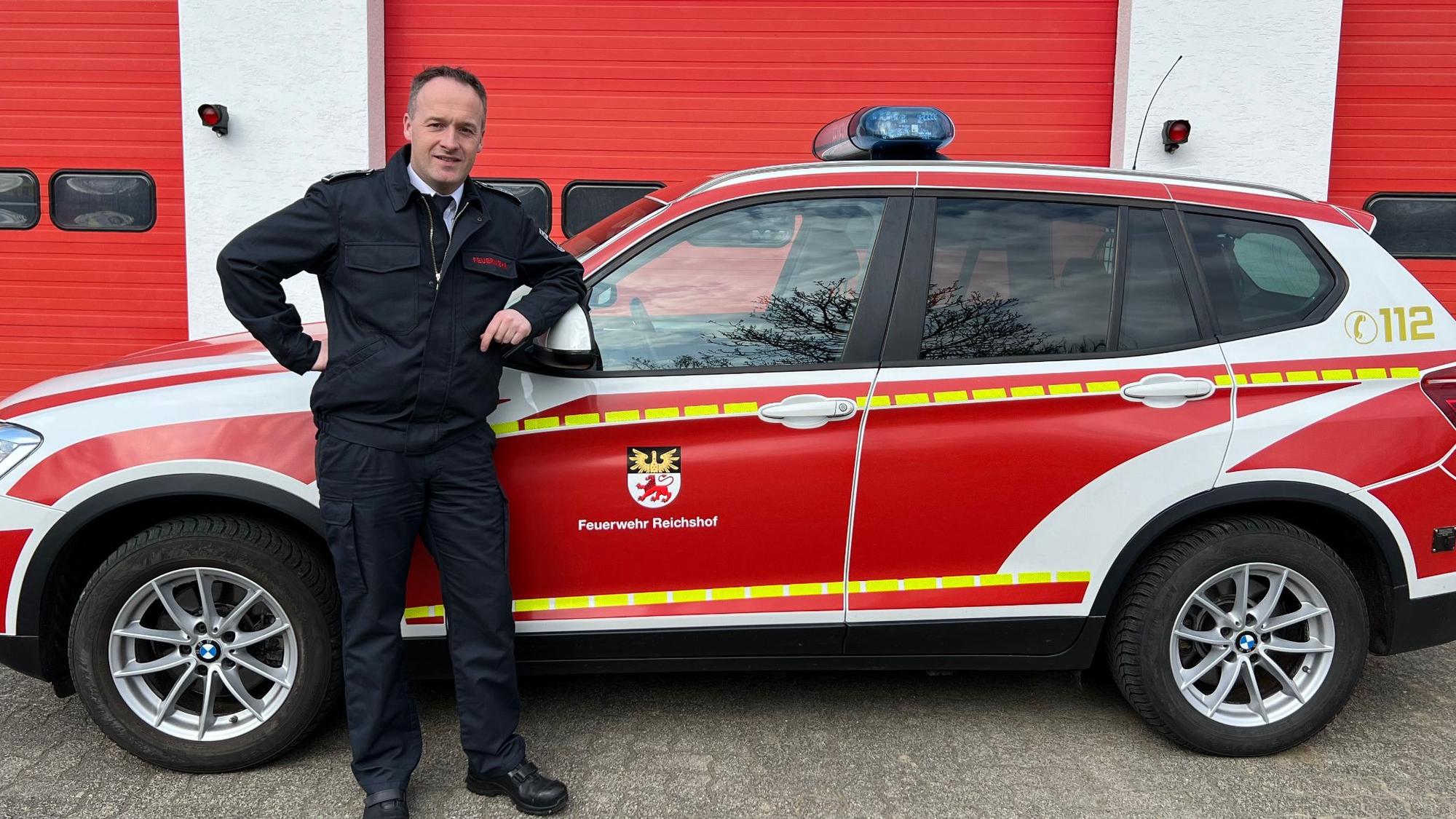 Sascha Frede posiert vor einem PKW der Feuerwehr.