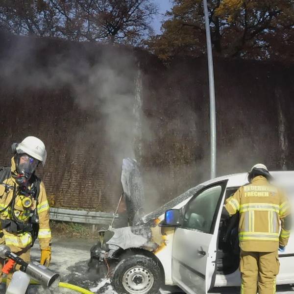 Aufnahme einer Bodycam. Zwei Feuerwehrmänner im Einsatz löschen einen weißen PKW.