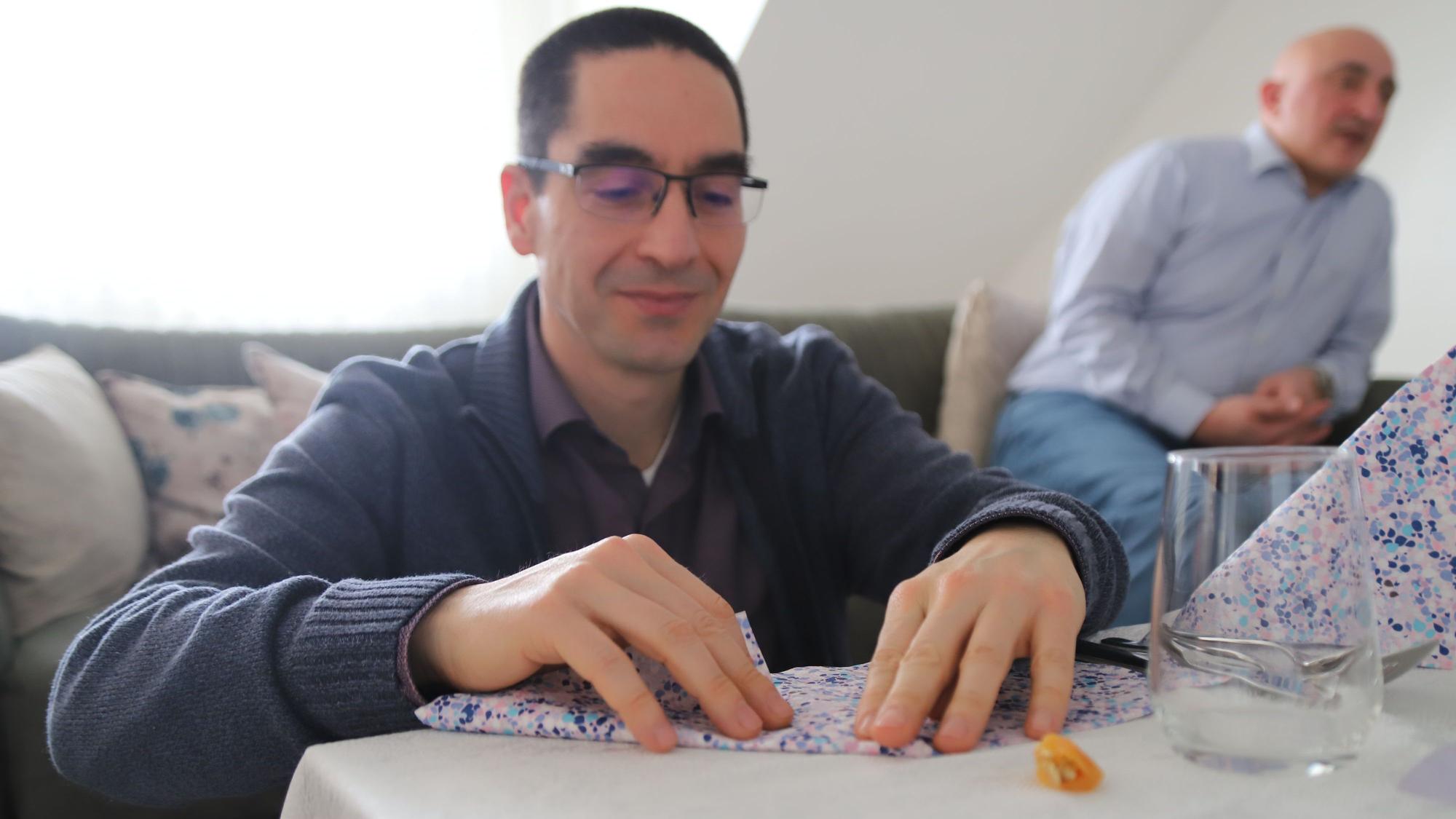 Semih Özenmis faltet im Wohnzimmer gewissenhaft die geblümten Servietten.