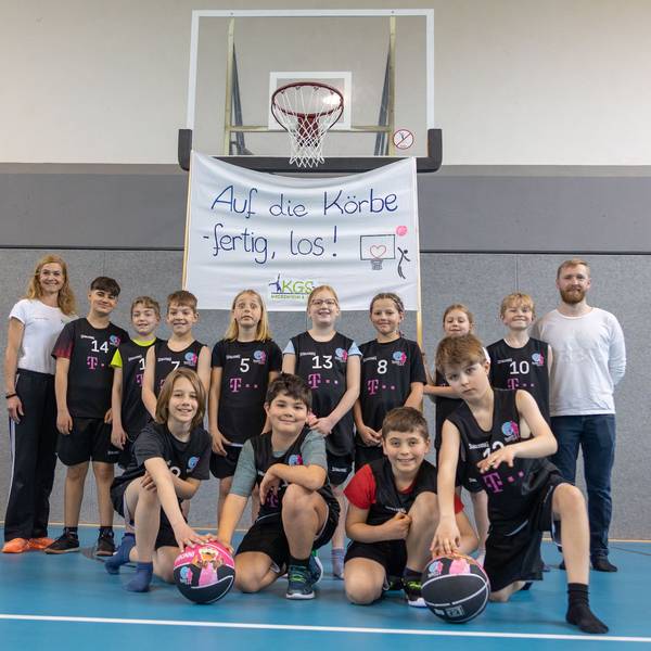 Die Sportlehrer Antje Rau und Daniel Miczka mit der Basketballmannschaft am 20.04.2023 bei der Vorstellung der neuen Trikots in der Katholischen Grundschule in Meckenheim. Foto Copyright: Petra Reuter