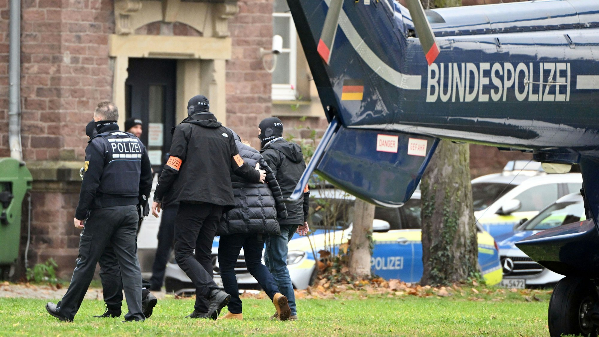 07.12.2022, Baden-Württemberg, Karlsruhe: Eine Person (2.v.r.) wird von Polizisten aus einem Hubschrauber gebracht.