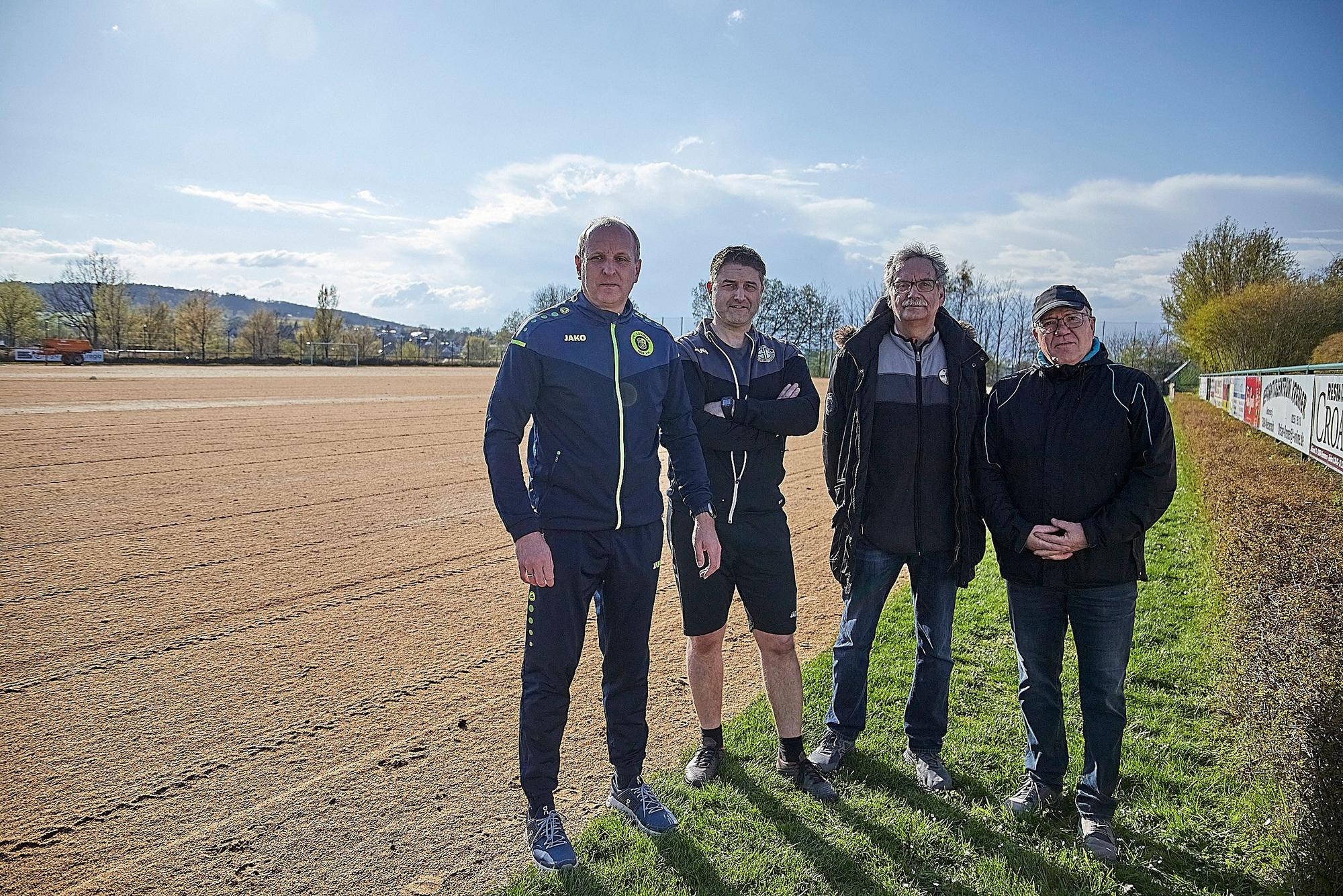 Die vier Vorstandsmitglieder am abgefrästen Sportplatz.