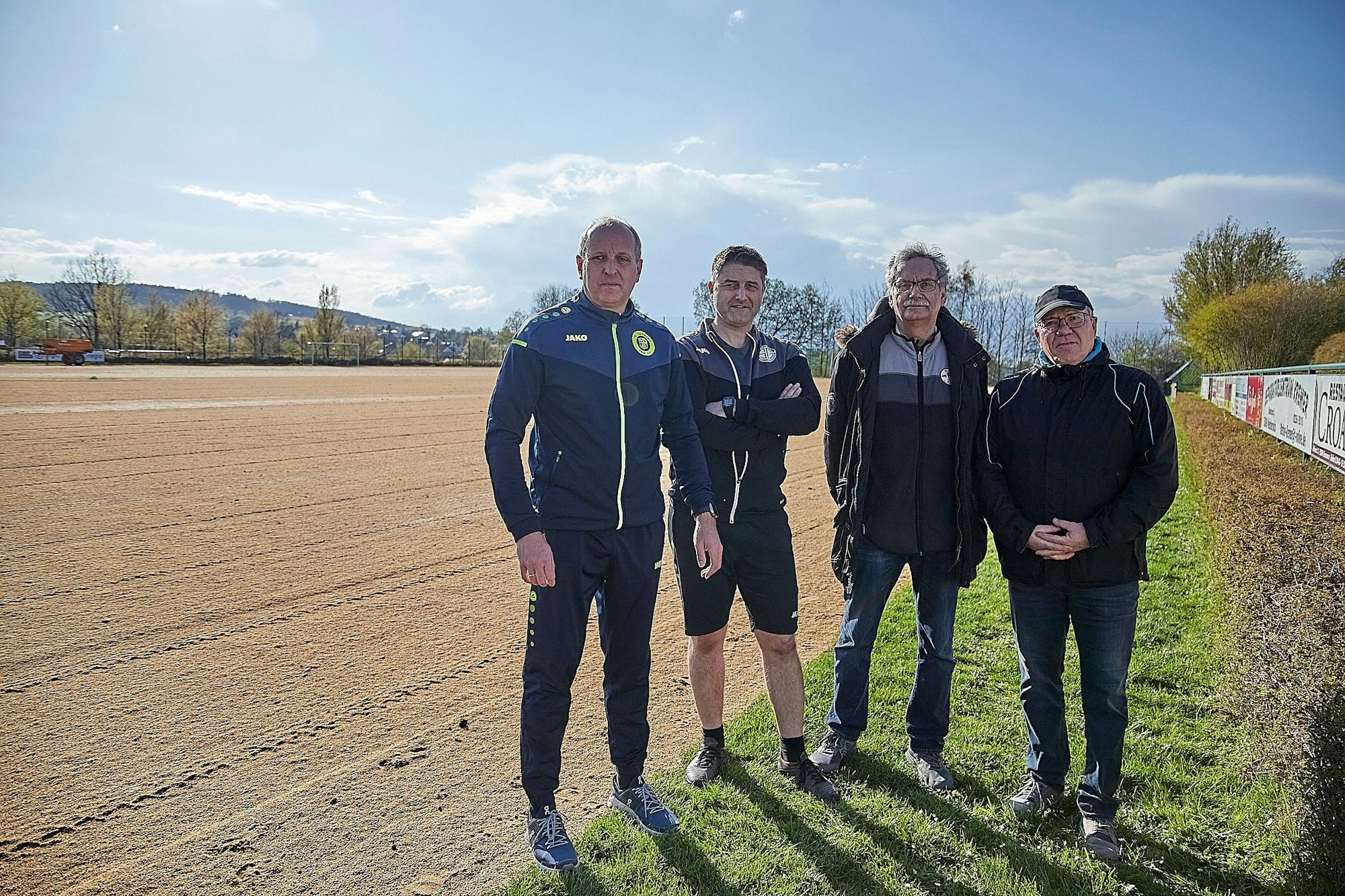 Die vier Vorstandsmitglieder am abgefrästen Sportplatz.