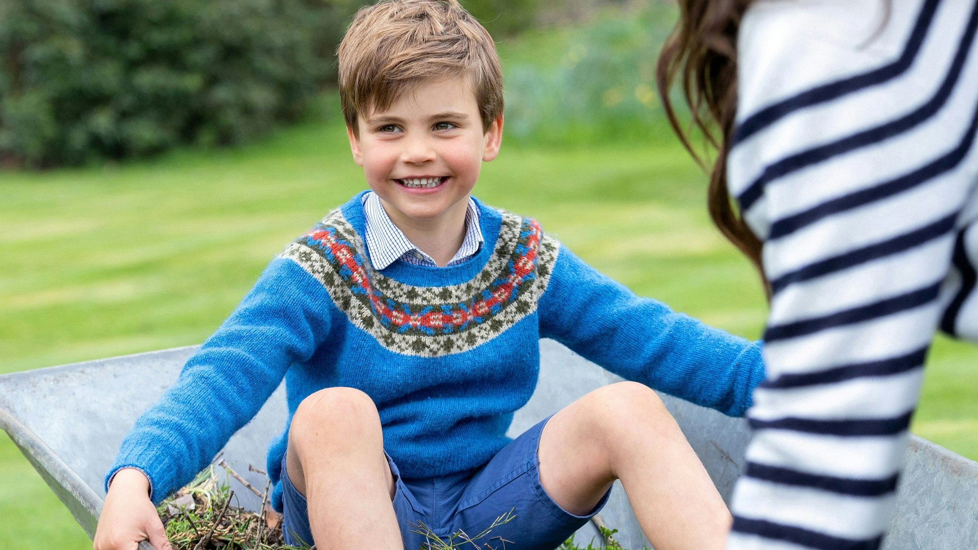 Dieses Bild zeigt Prinz Louis, der am Sonntag seinen fünften Geburtstag feiert. Prinz Louis sitzt in einer Schubkarre, die seine Mutter, die Prinzessin von Wales, schiebt.