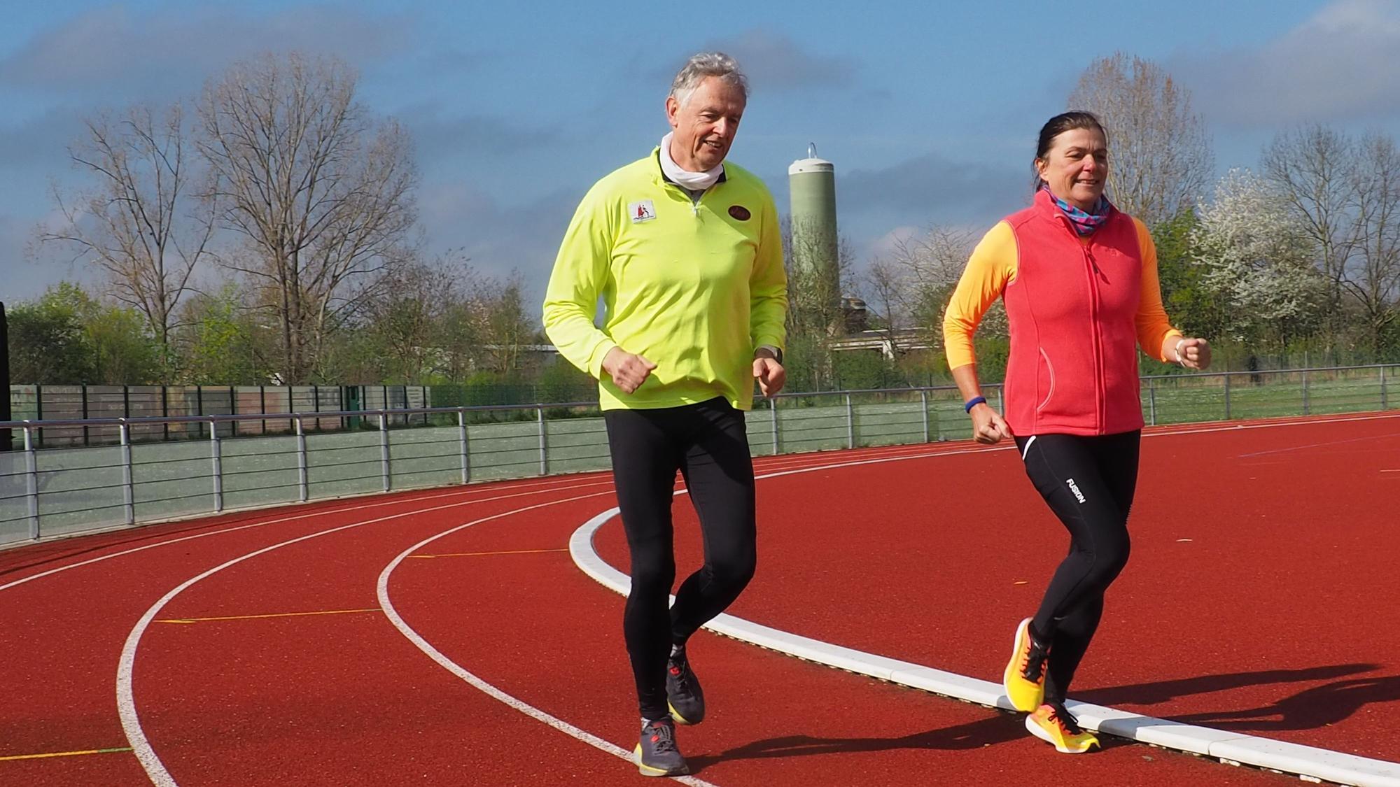Gerhard Illian und Claudia Hartmann nutzen das neue Angebot der Stadt. Ein Mann und eine Frau laufen auf der Laufbahn des Sportplatzes.