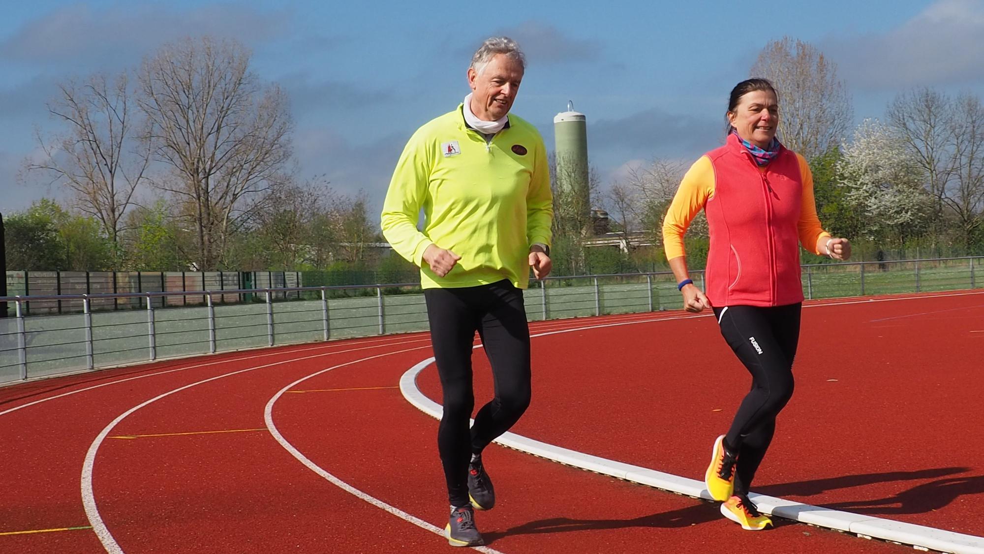Gerhard Illian und Claudia Hartmann nutzen das neue Angebot der Stadt. Ein Mann und eine Frau laufen auf der Laufbahn des Sportplatzes.
