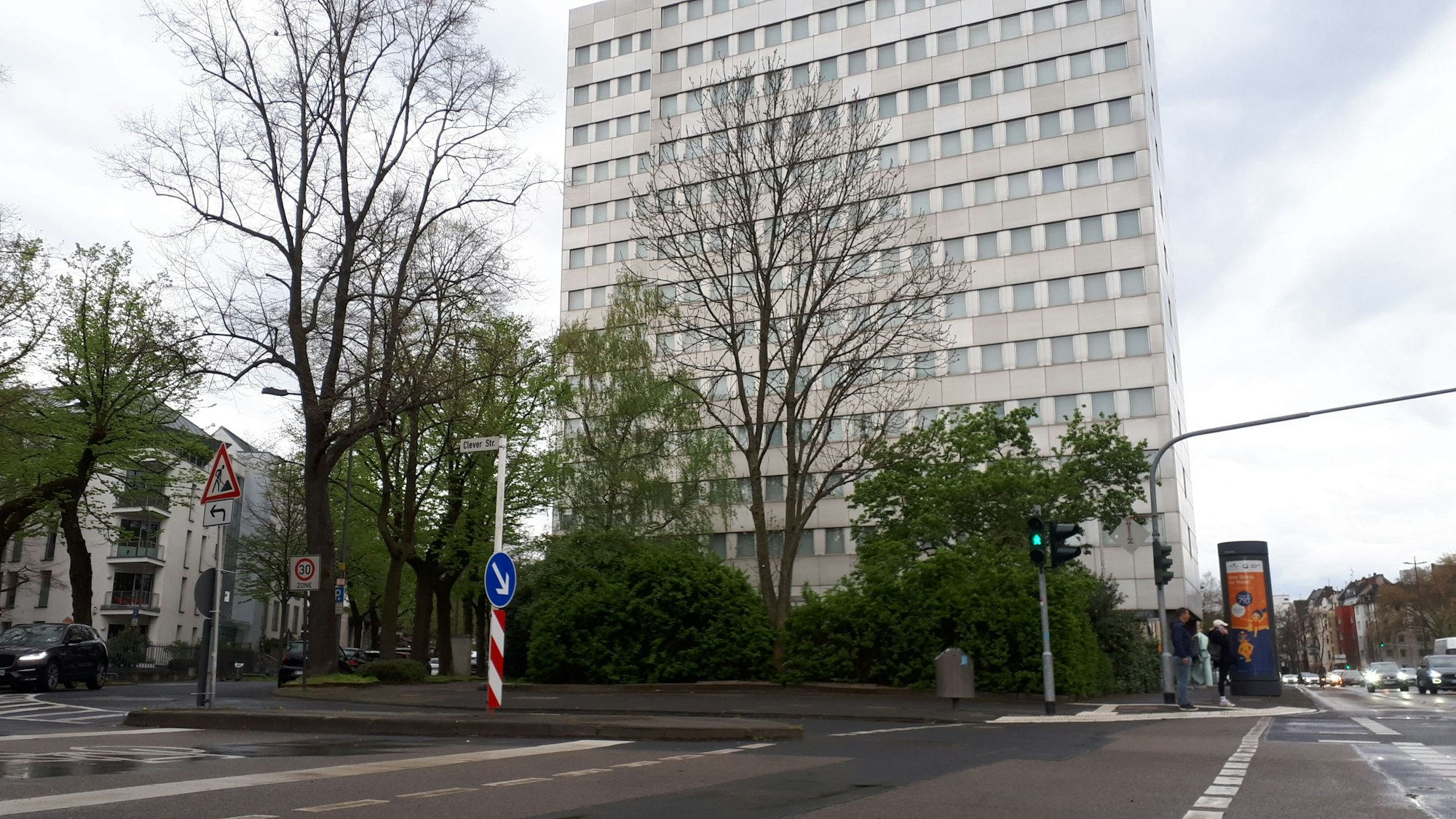 Ein großes weißes Hochhaus steht an einer Kreuzung.