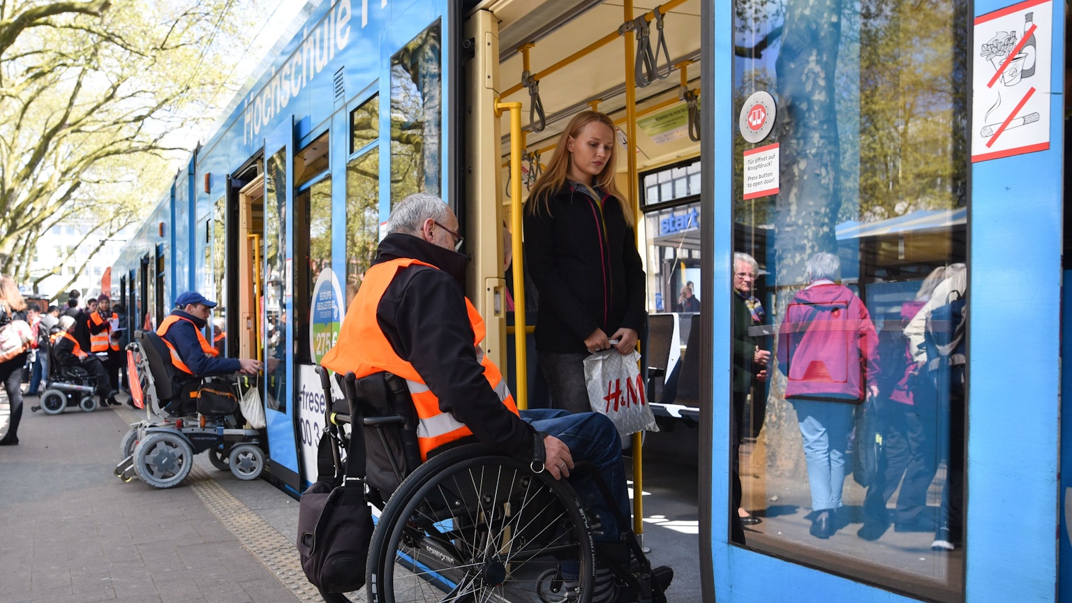 Ein Mann im Rollstuhl versucht in eine Straßenbahn zu fahren.