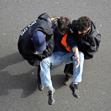 Ein Aktivist wird in Berlin von zwei Polizisten von der Fahrbahn der A100 getragen. Am Montag hat die „Letzte Generation“ nach eigenen Angaben versucht, die Hauptstadt lahmzulegen.
